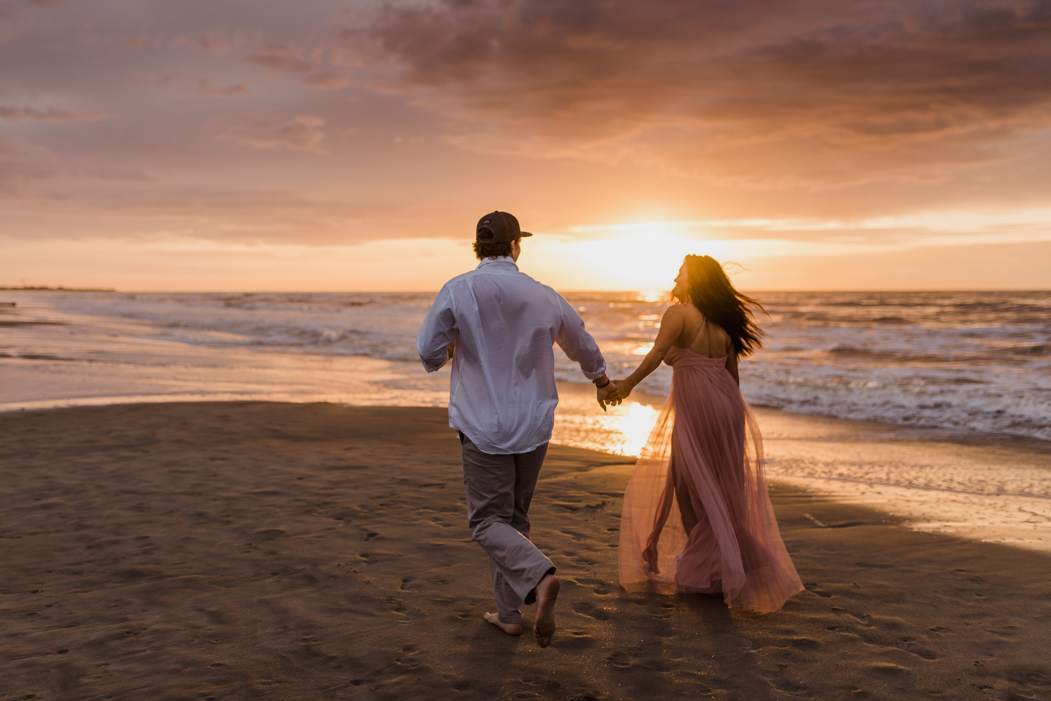A couple running along Folly Beach during their sunrise engagement session