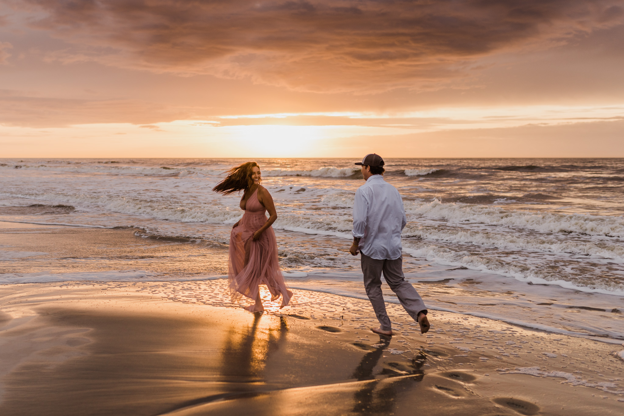 A couple running along Folly Beach during their sunrise engagement session