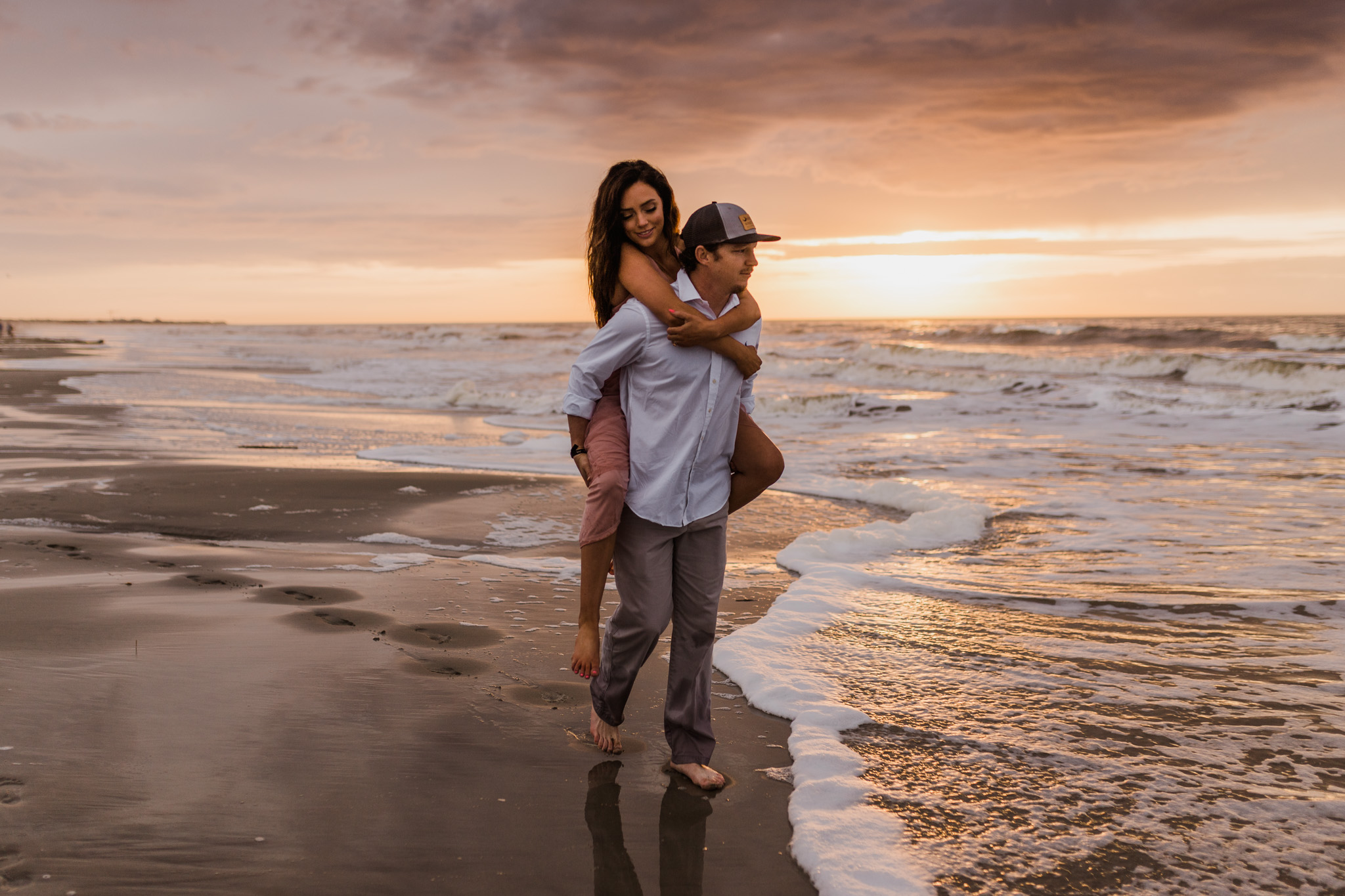 A couple walks along the edge of the beach together during their sunrise engagement session