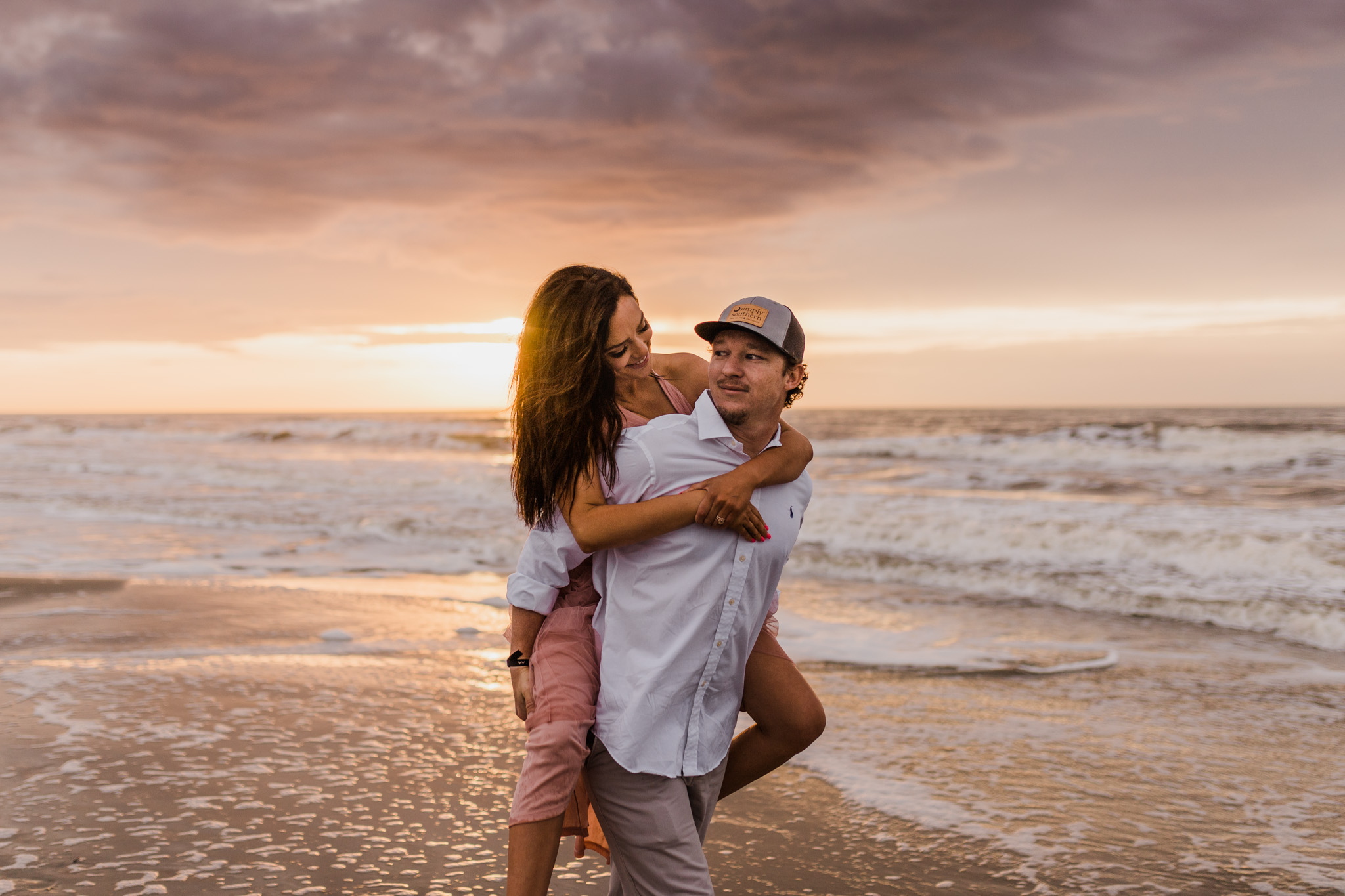 A couple walks along the edge of the beach together during their sunrise engagement session