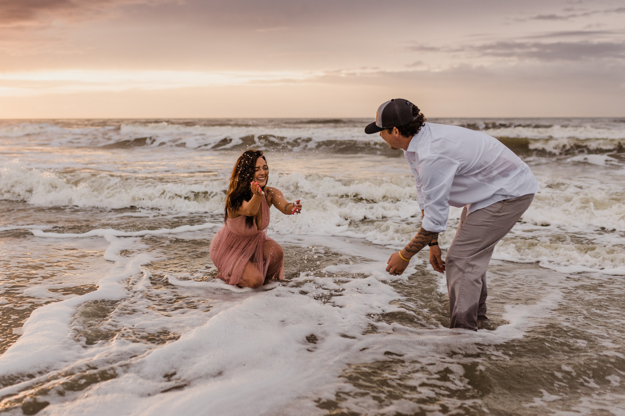 A couple plays in the waves during their Folly Beach engagement session