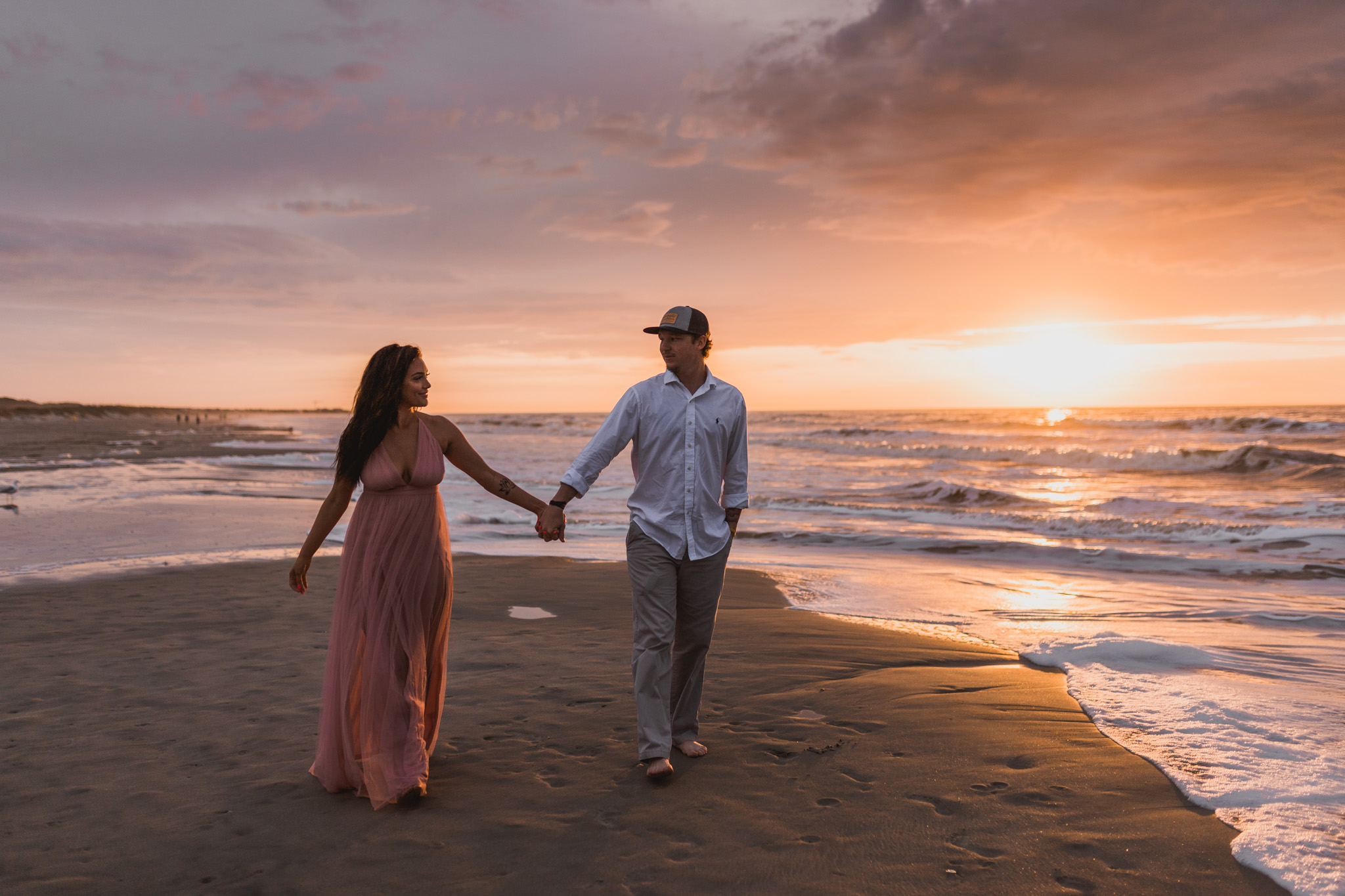 A couple walking along Folly Beach during their sunrise engagement session