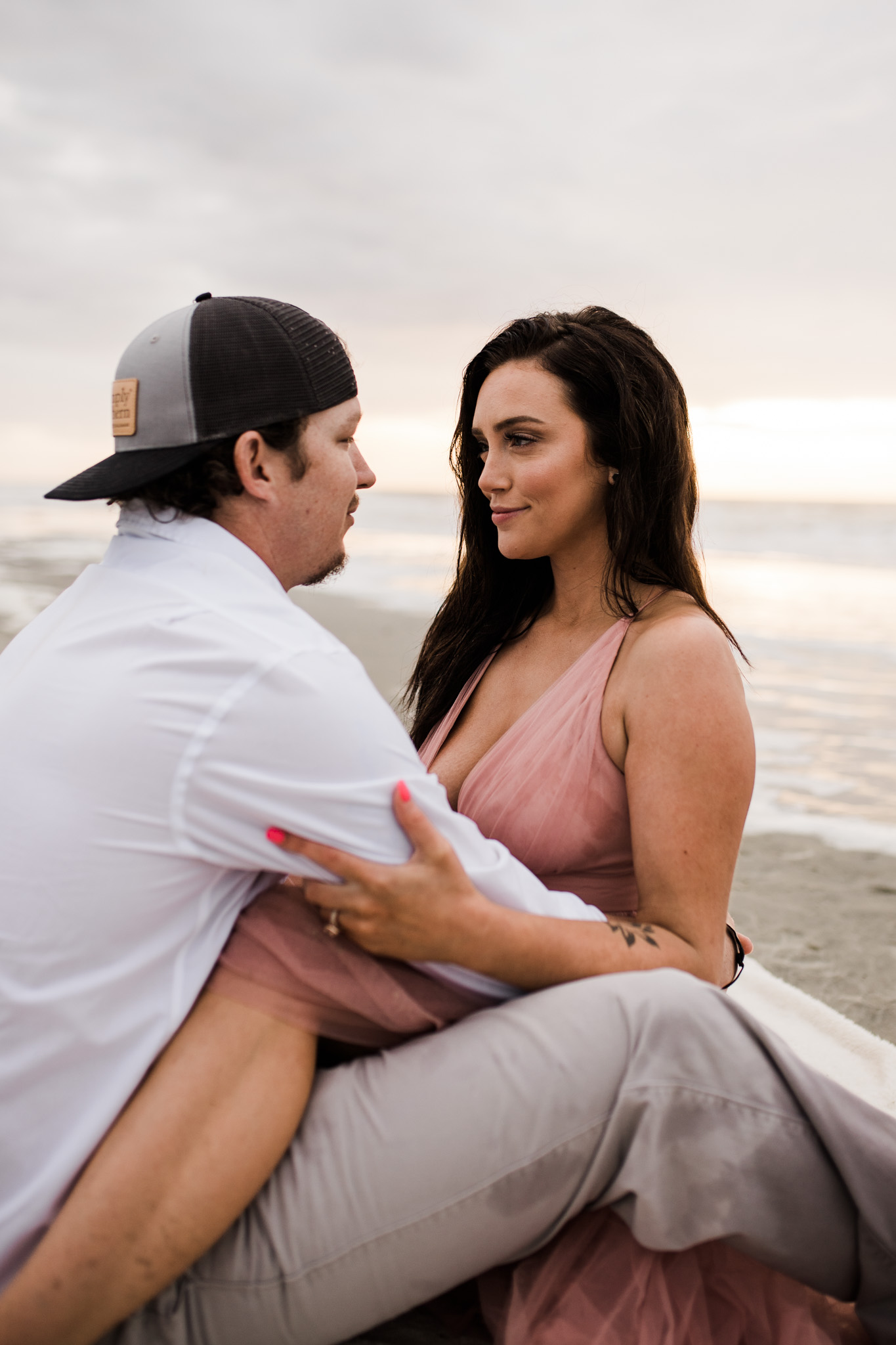 A couple snuggles on the beach during their sunrise engagement session in Charleston, South Carolina