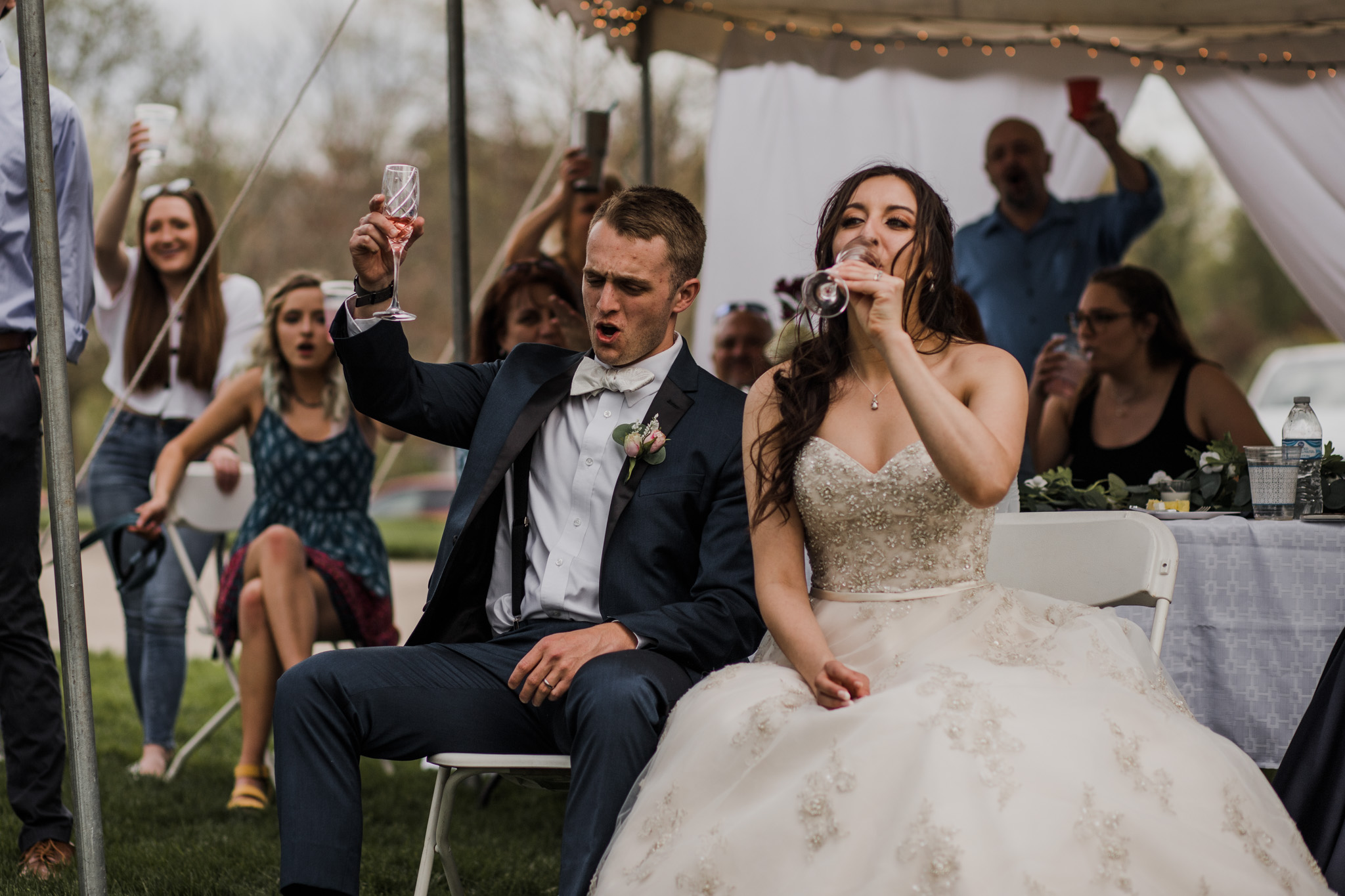 Bride and groom toasting speeches and drinking champagne during their Indiana backyard wedding.