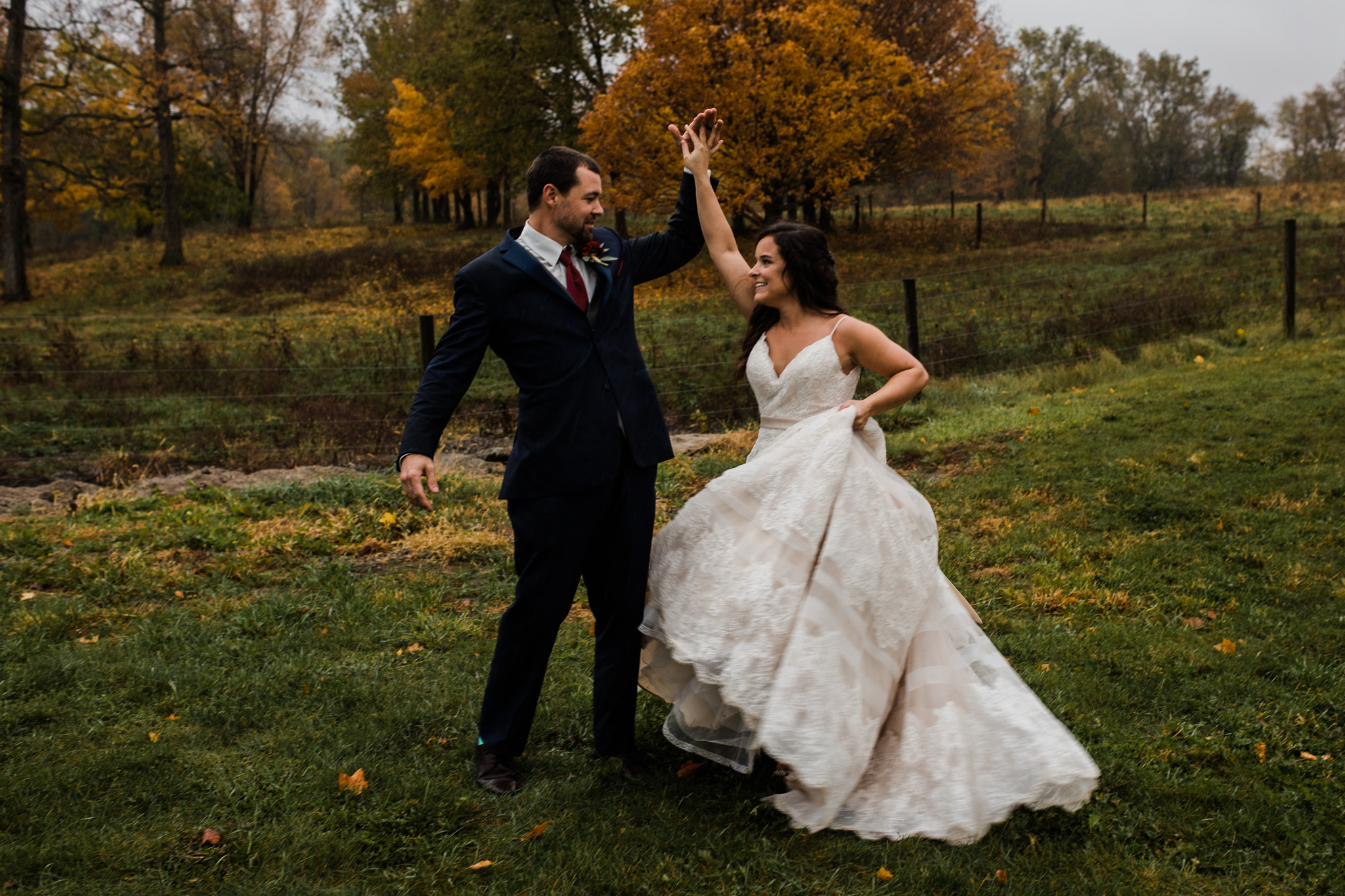Bride and groom dancing in the autumn rain at their bison ranch wedding.