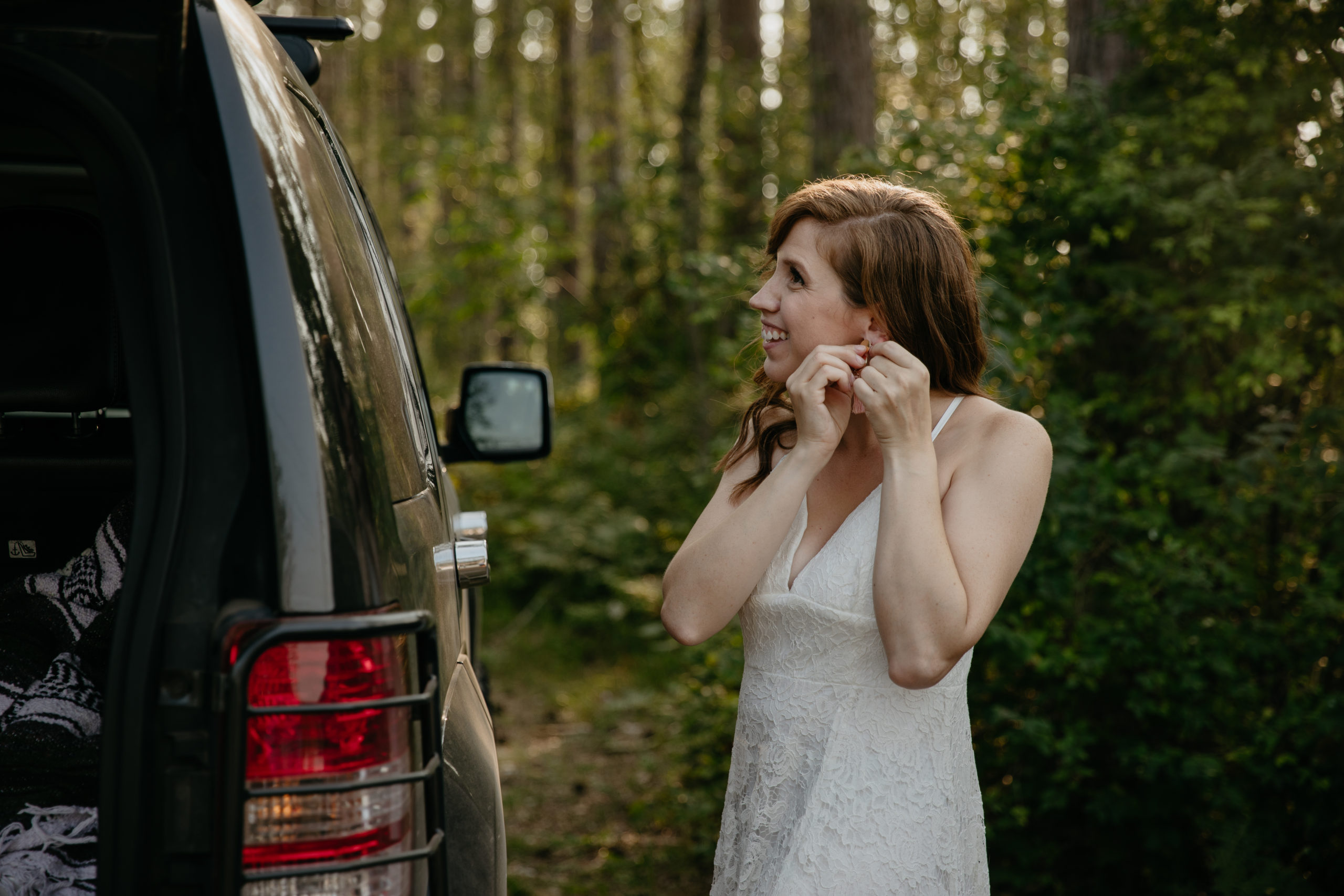 The bride putting on earrings before their forest elopement in Michigan