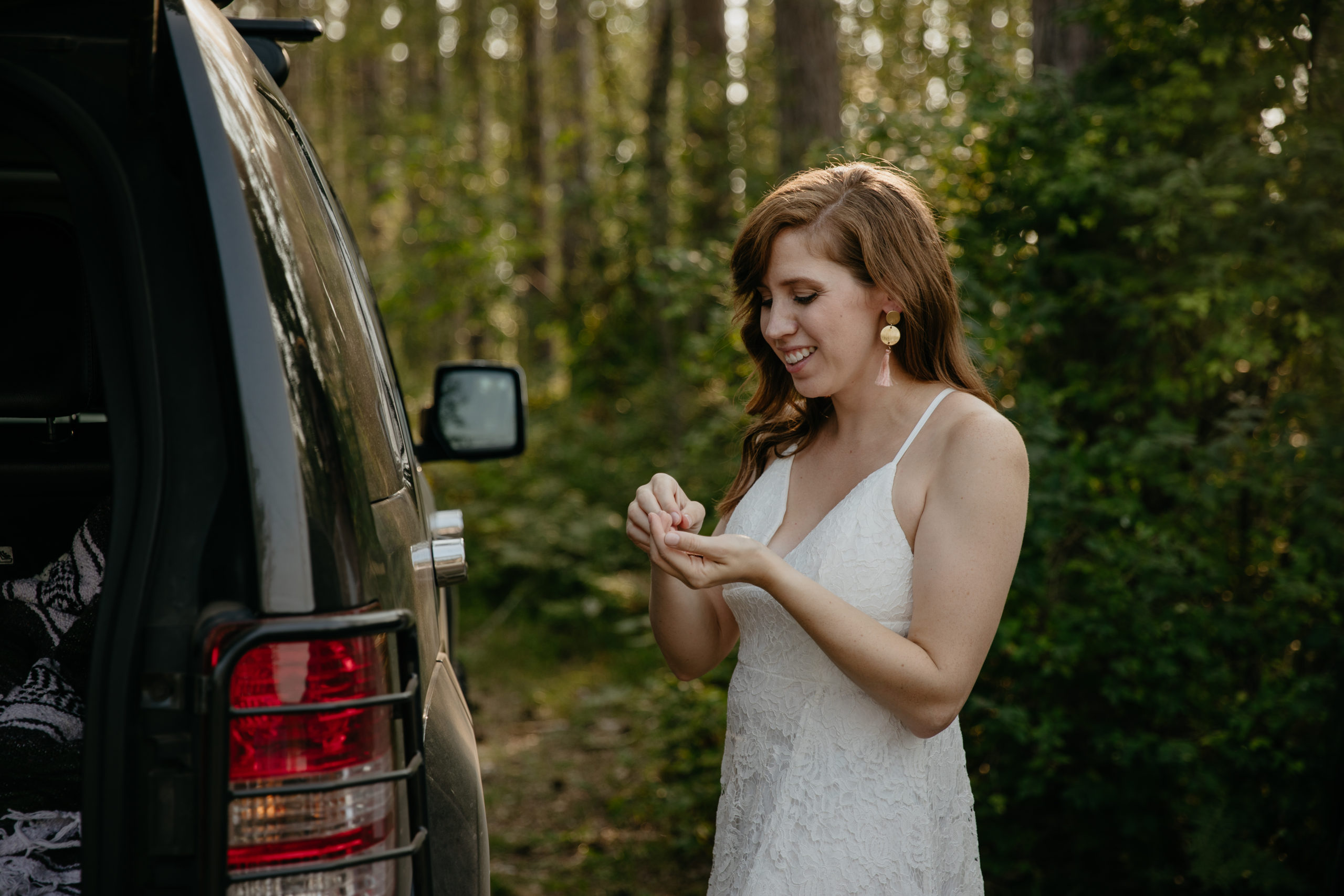 The bride putting on earrings before their forest elopement in Michigan