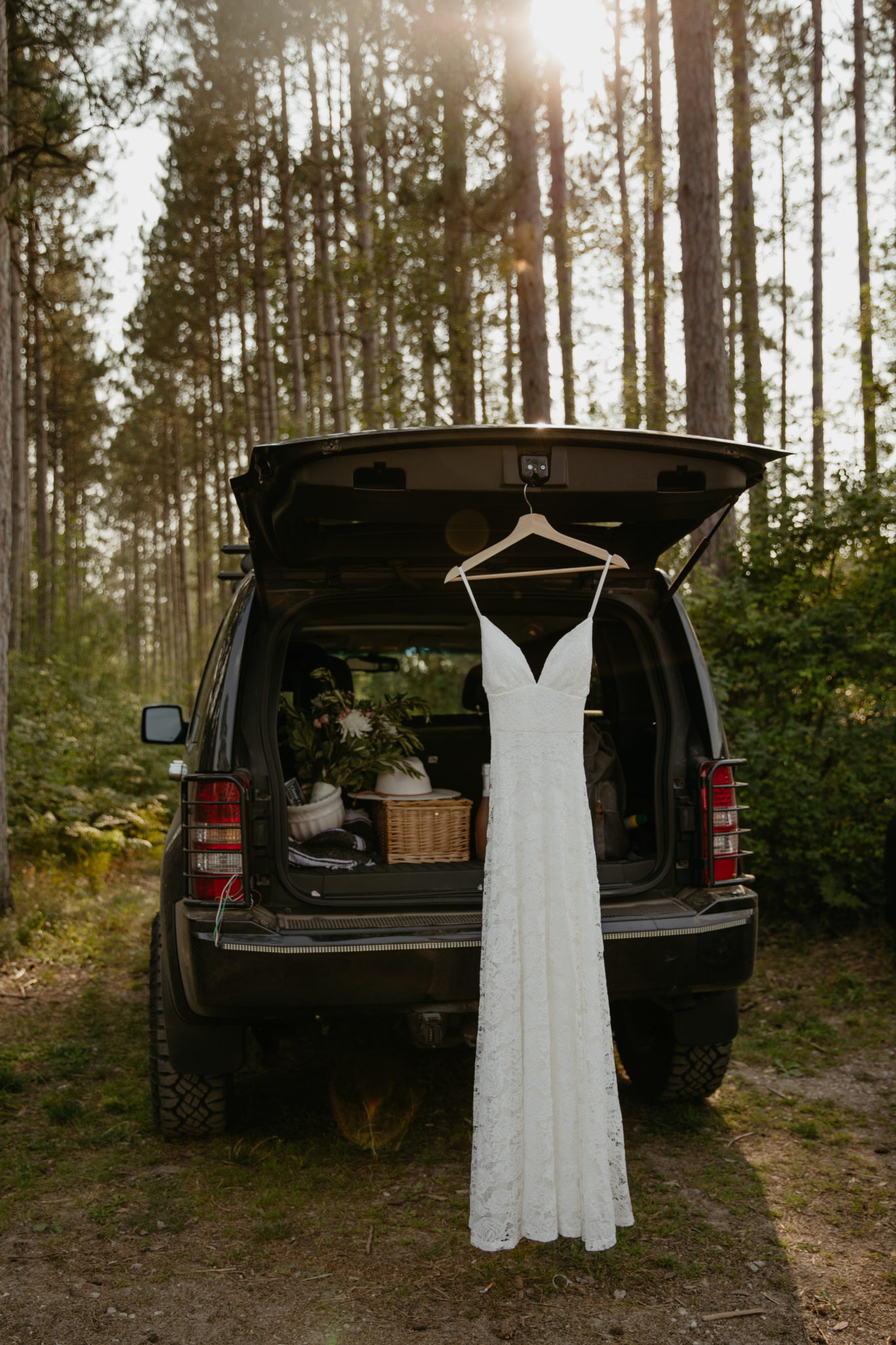 Wedding dress hanging from a jeep during this forest elopement for