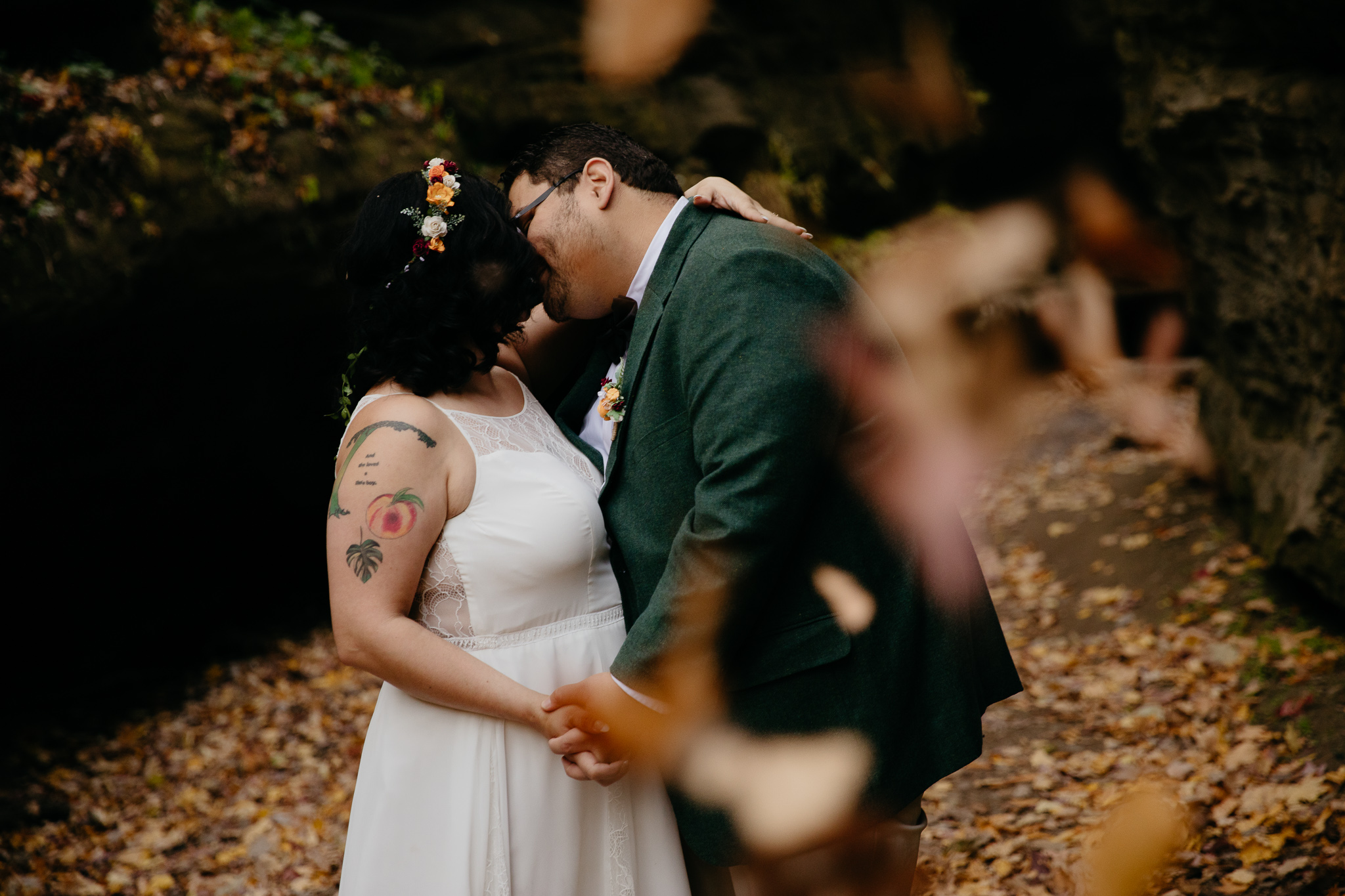 Leaves falling as bride and groom kiss during their fall elopement at Turkey Run State Park