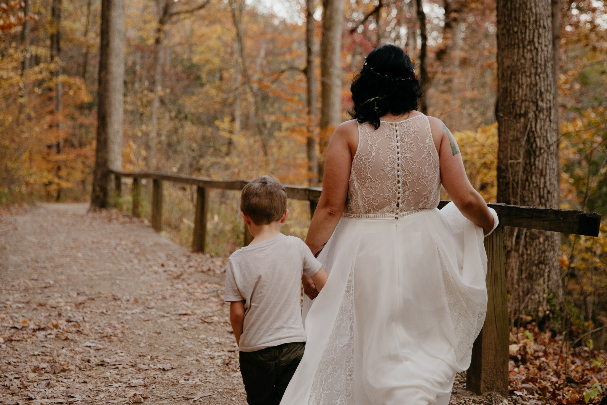Leaves falling as bride and groom hike with their son during their fall elopement at Turkey Run State Park