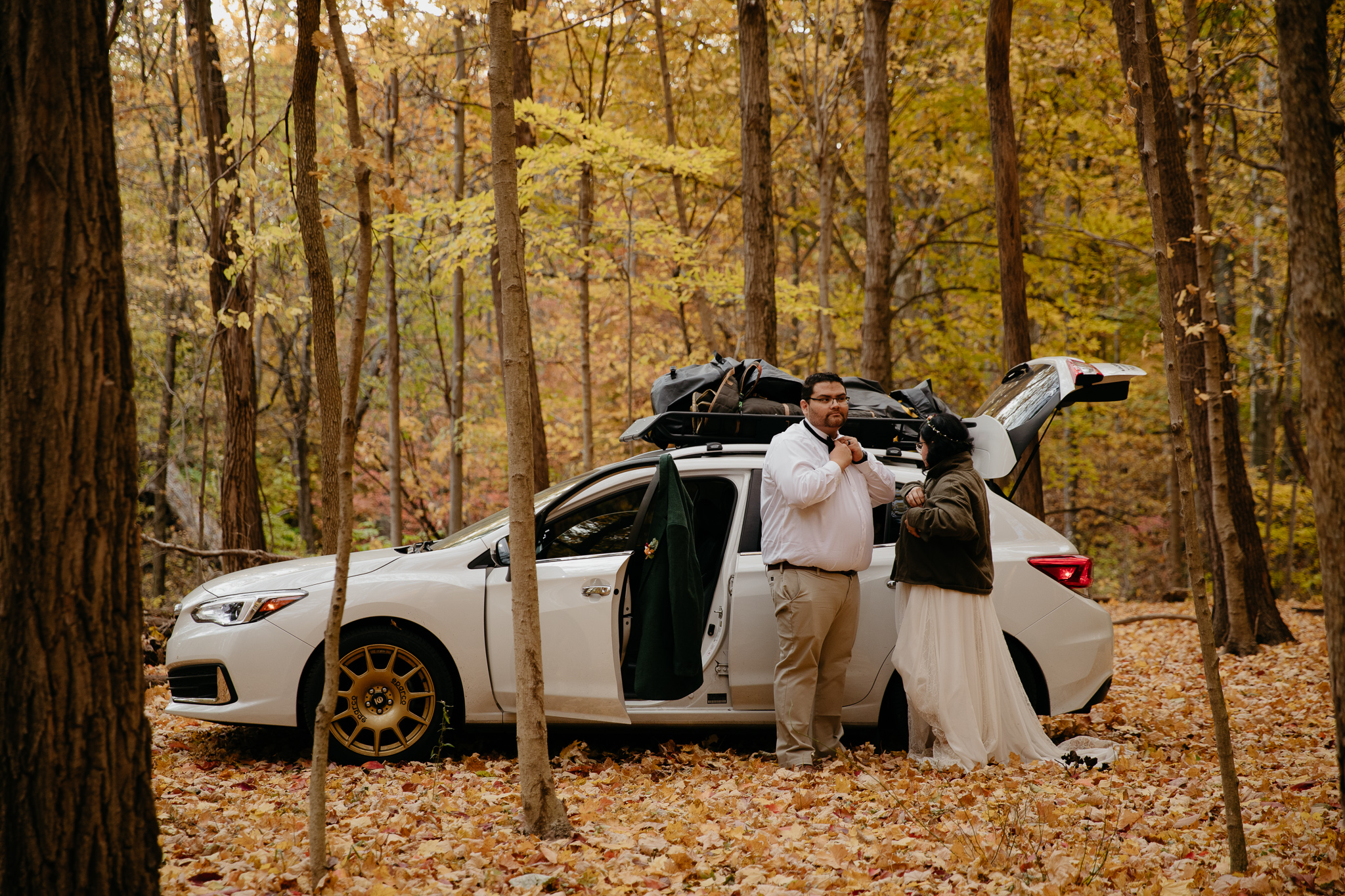 Bride and groom get dressed by their car at a campsite during their fall Indiana Elopement