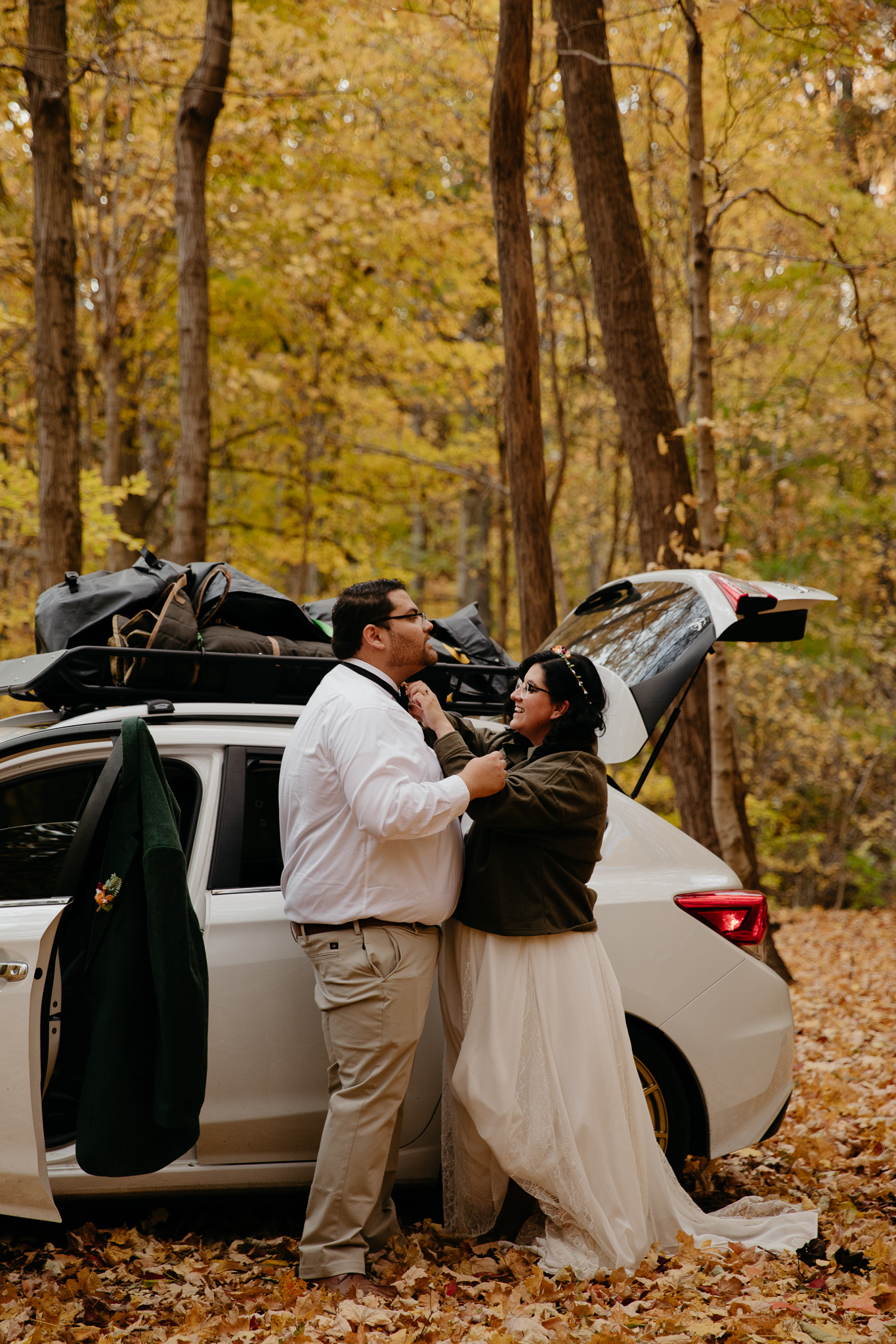 Bride and groom get dressed by their car at a campsite during their fall Indiana Elopement
