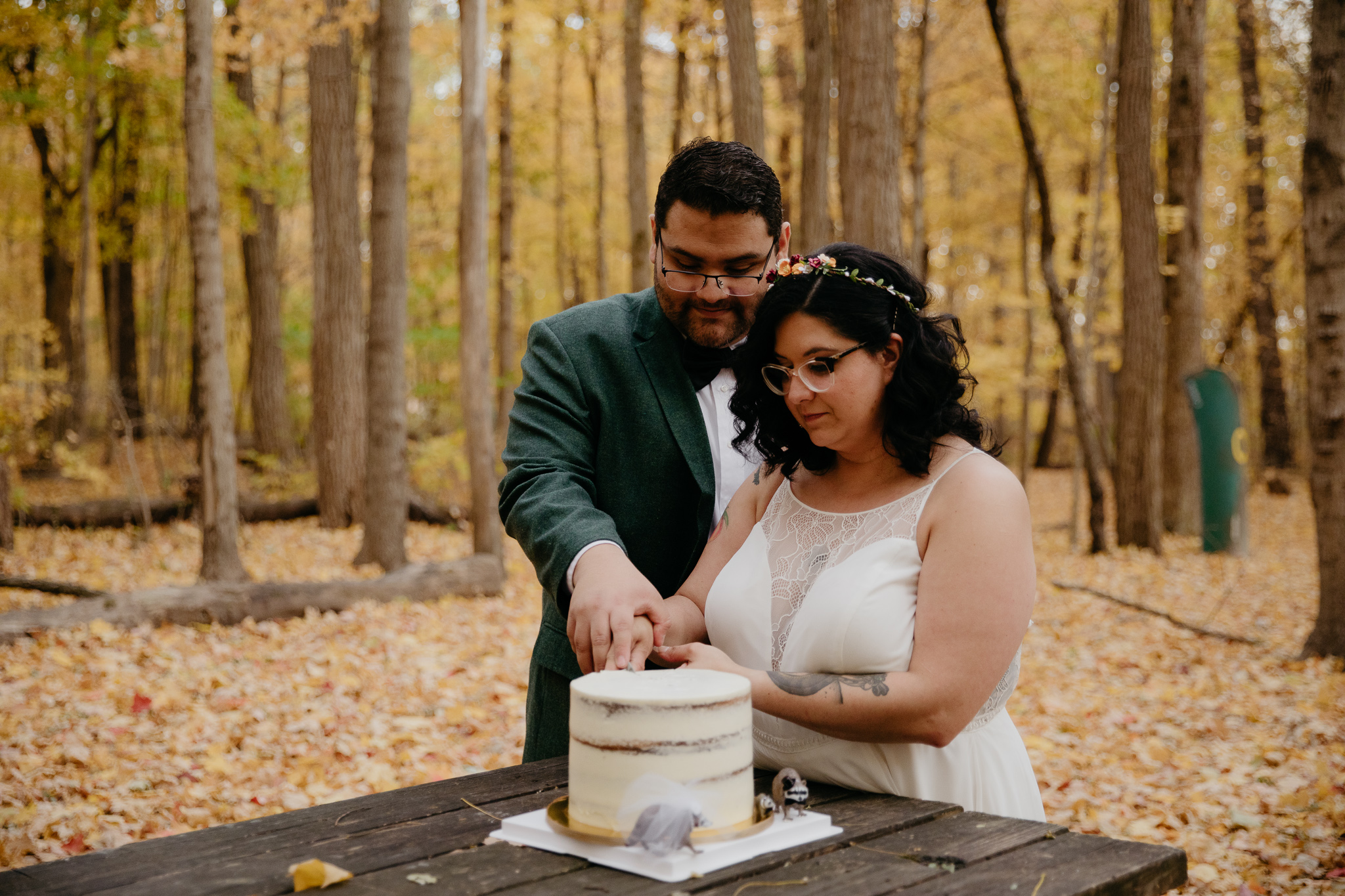 Bride and groom cutting wedding cake at campsite during their autumn Indiana elopement