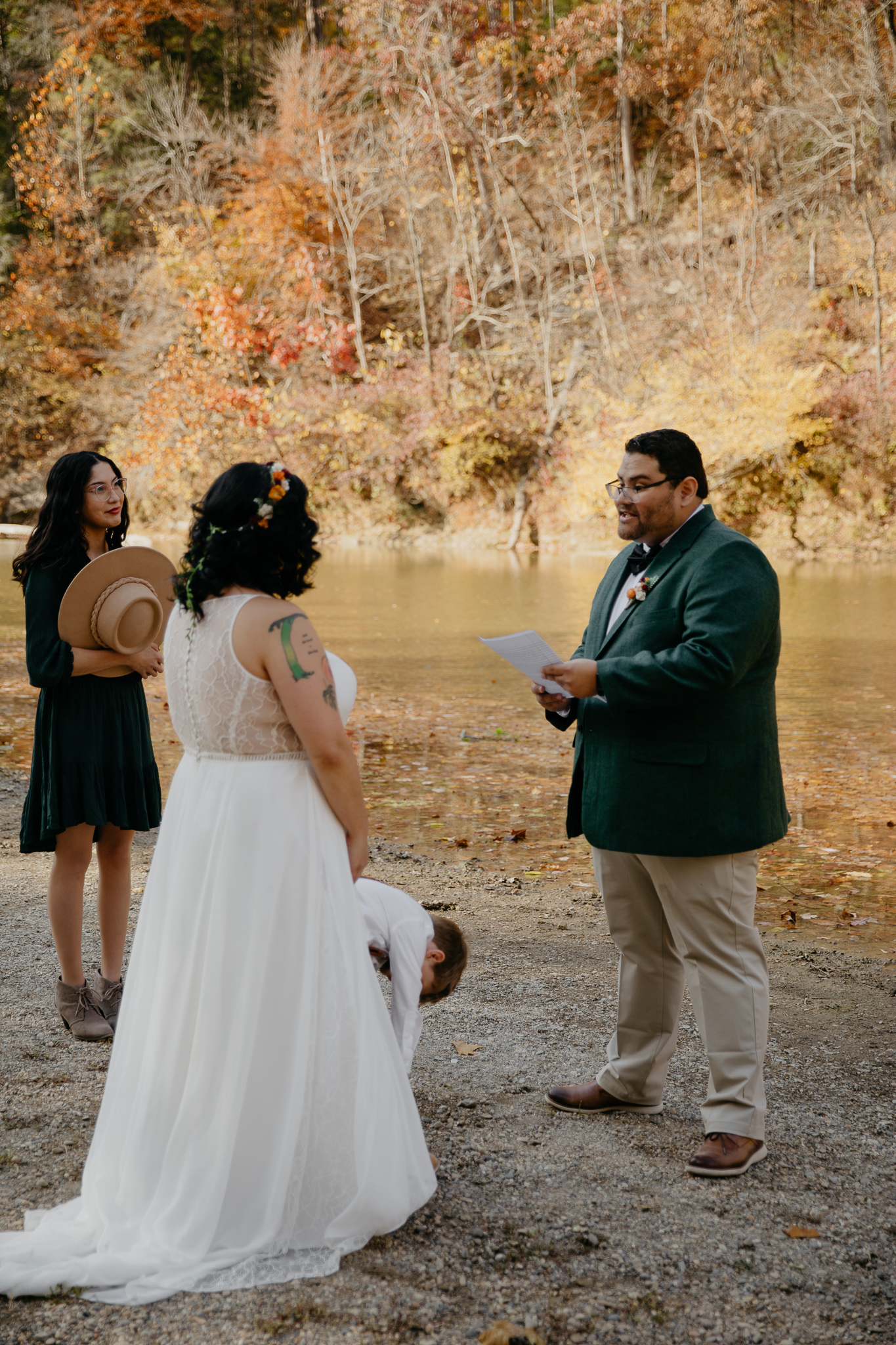 A groom shares his vows with his bride and son at their autumn elopement in Turkey Run State Park, Indiana