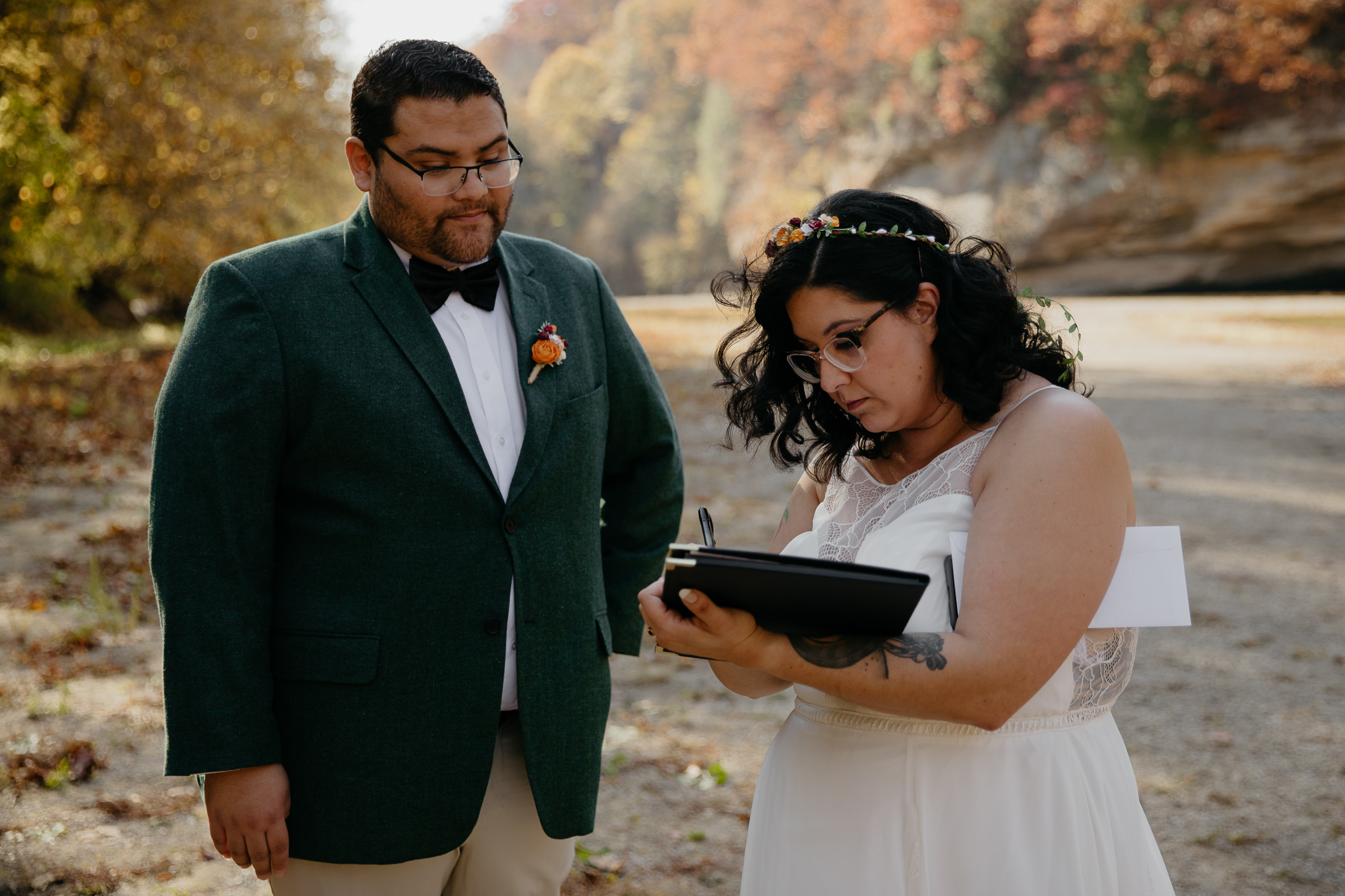 A groom and bride sign their marriage license after their fall elopement ceremony at Sugar Creek, Indiana