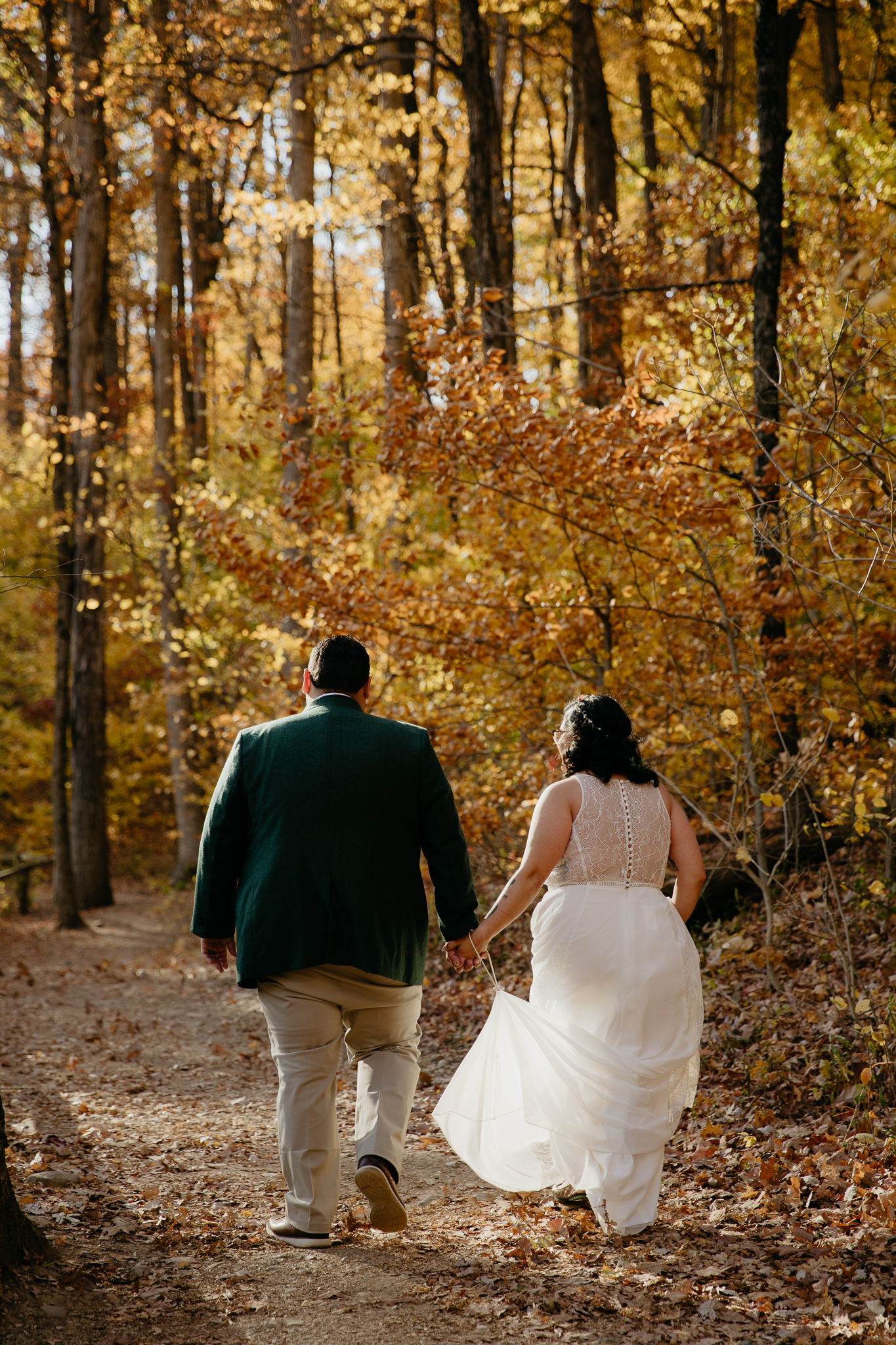 Bride and groom walking through the autumn woods at Turkey Run State Park, holding hands