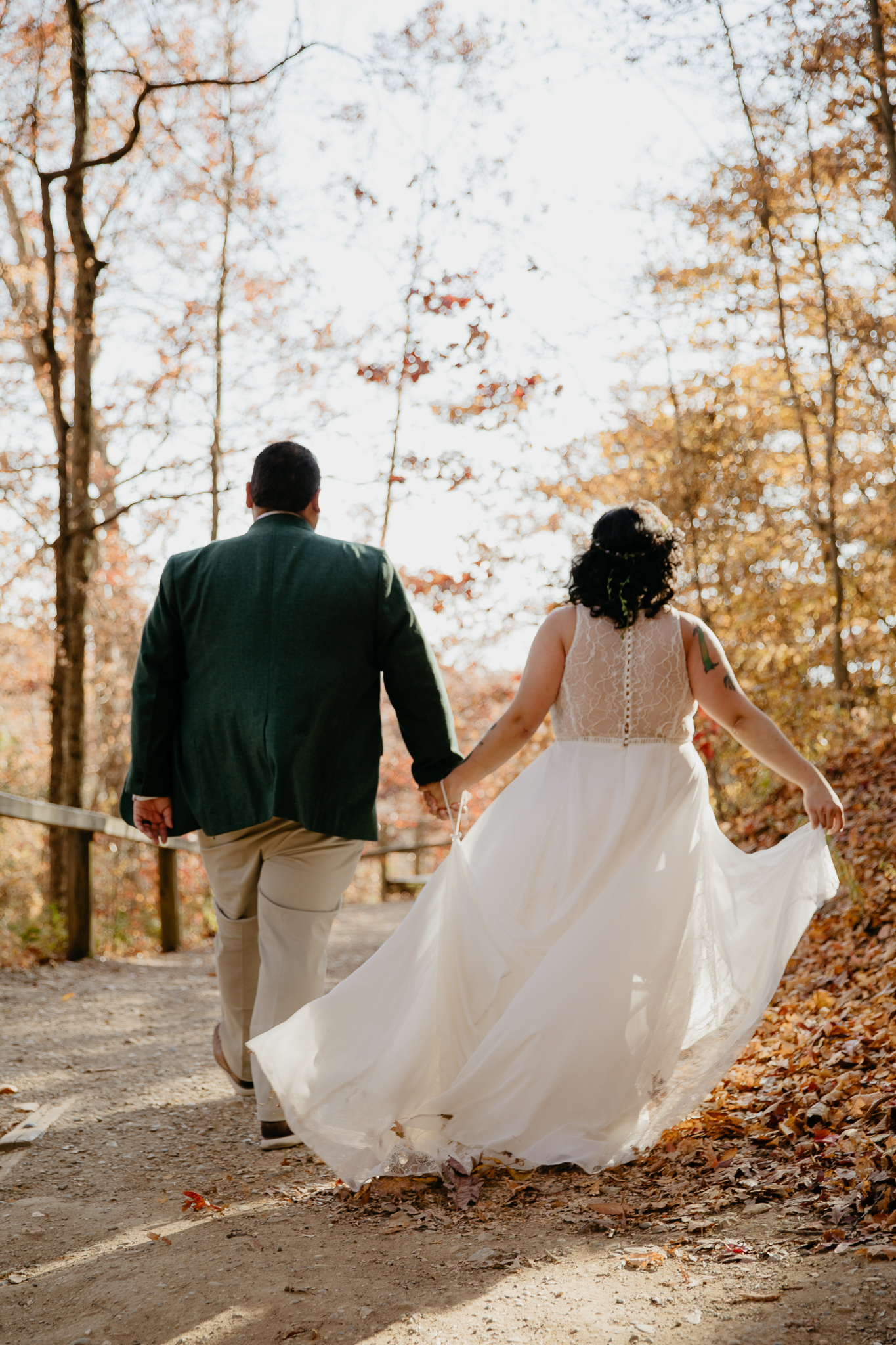 Bride and groom walking through the autumn woods at Turkey Run State Park, holding hands