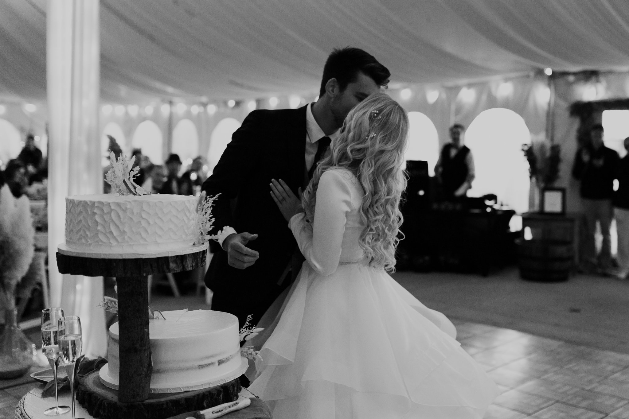 Bride and groom kiss in a white tent during their October wedding reception