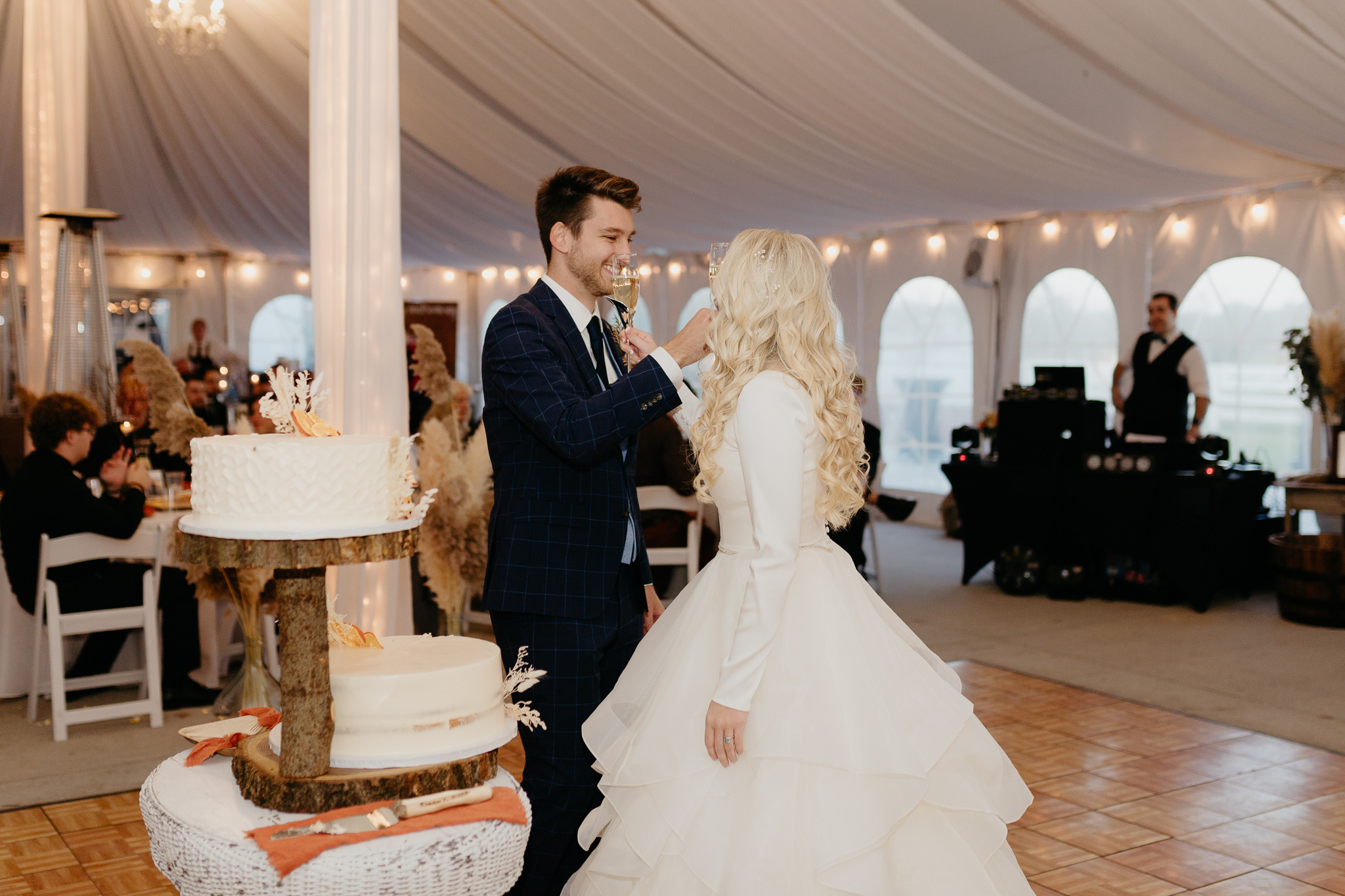 Bride and groom toast champagne in a white tent during their October wedding reception