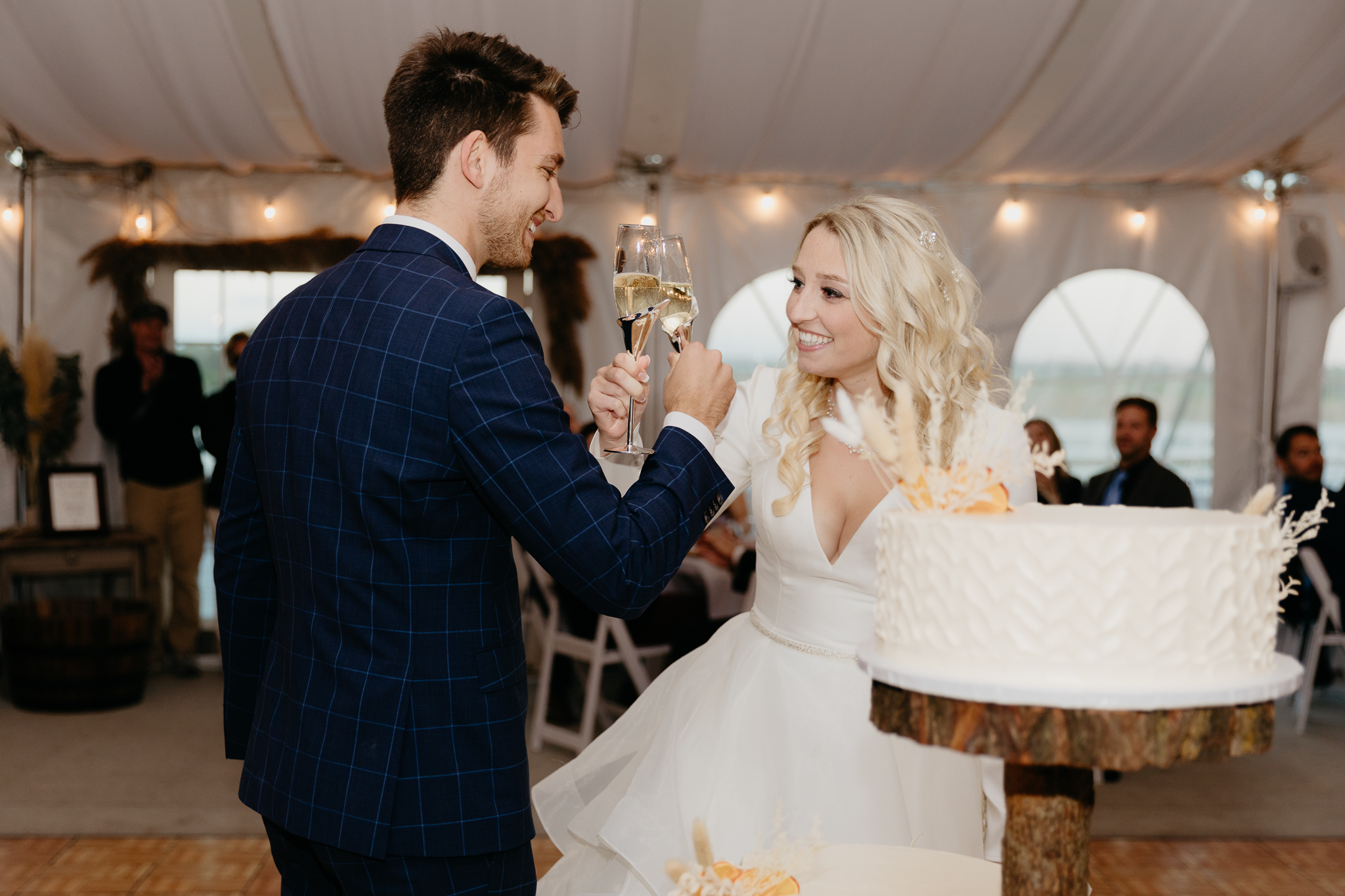 Bride and groom toast champagne in a white tent during their October wedding reception