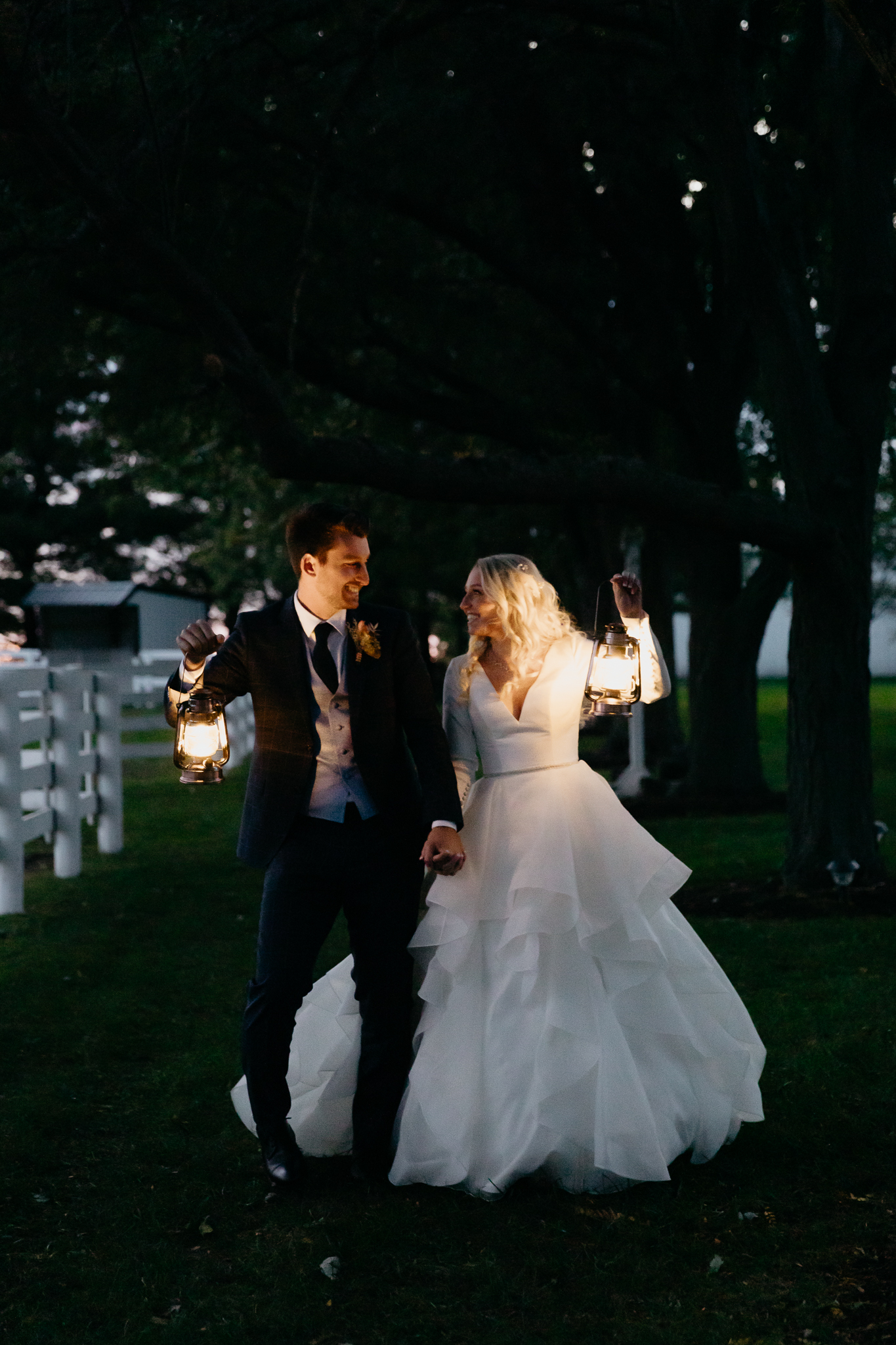 Bride and groom kissing in the dark outdoors, holding lanterns next to each other