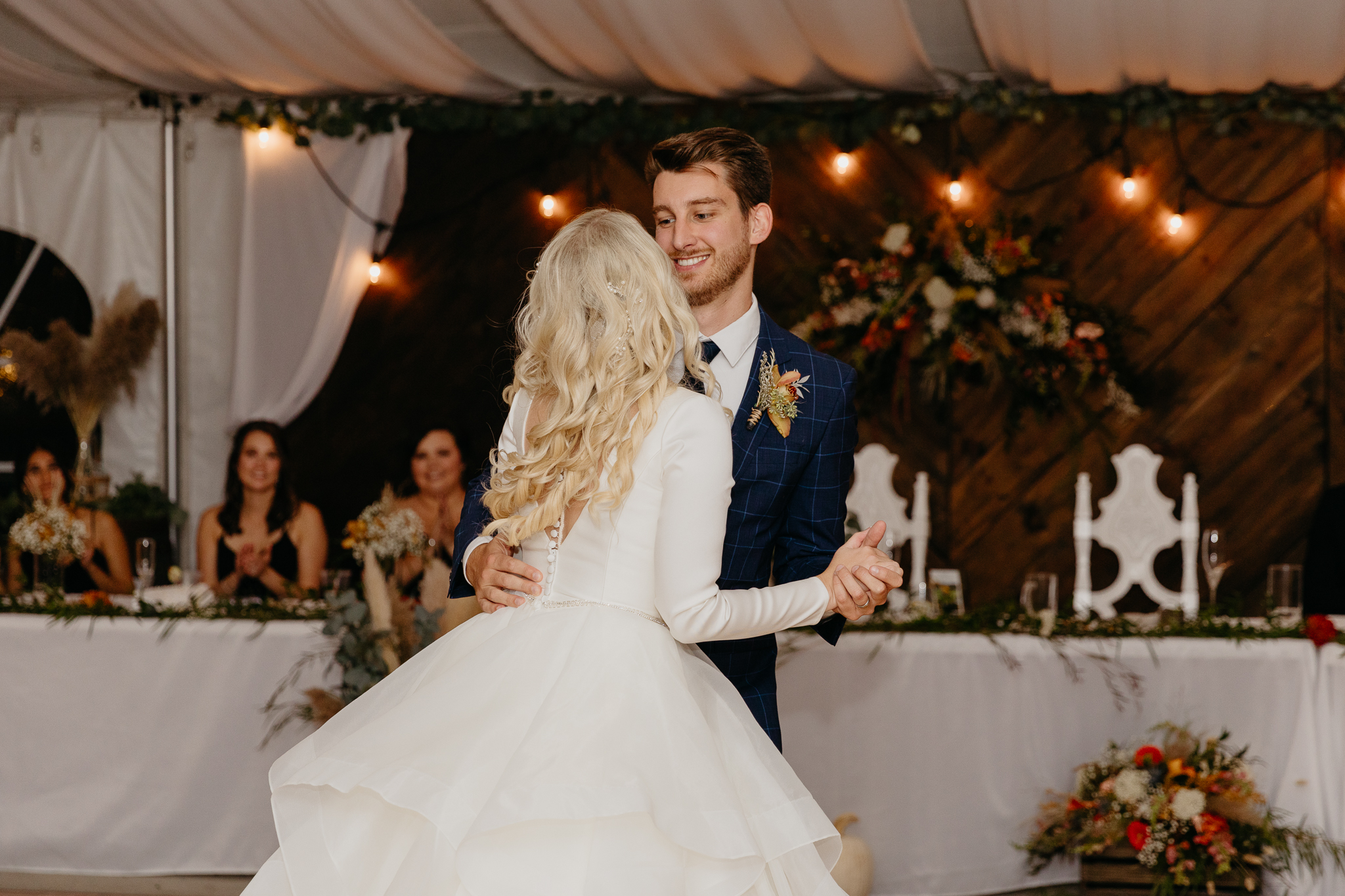 Bride and groom dancing together during their first dance, in a white tent wedding