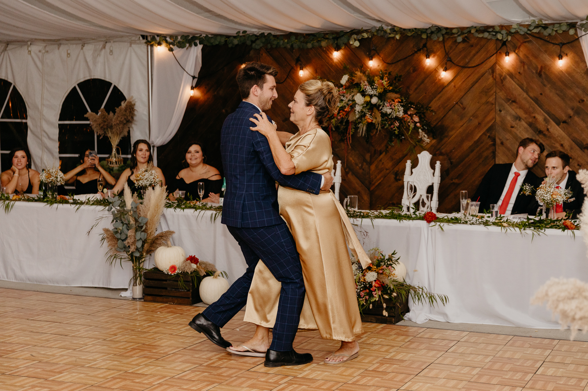 Groom dances with his mother on the dancefloor in a white tent wedding