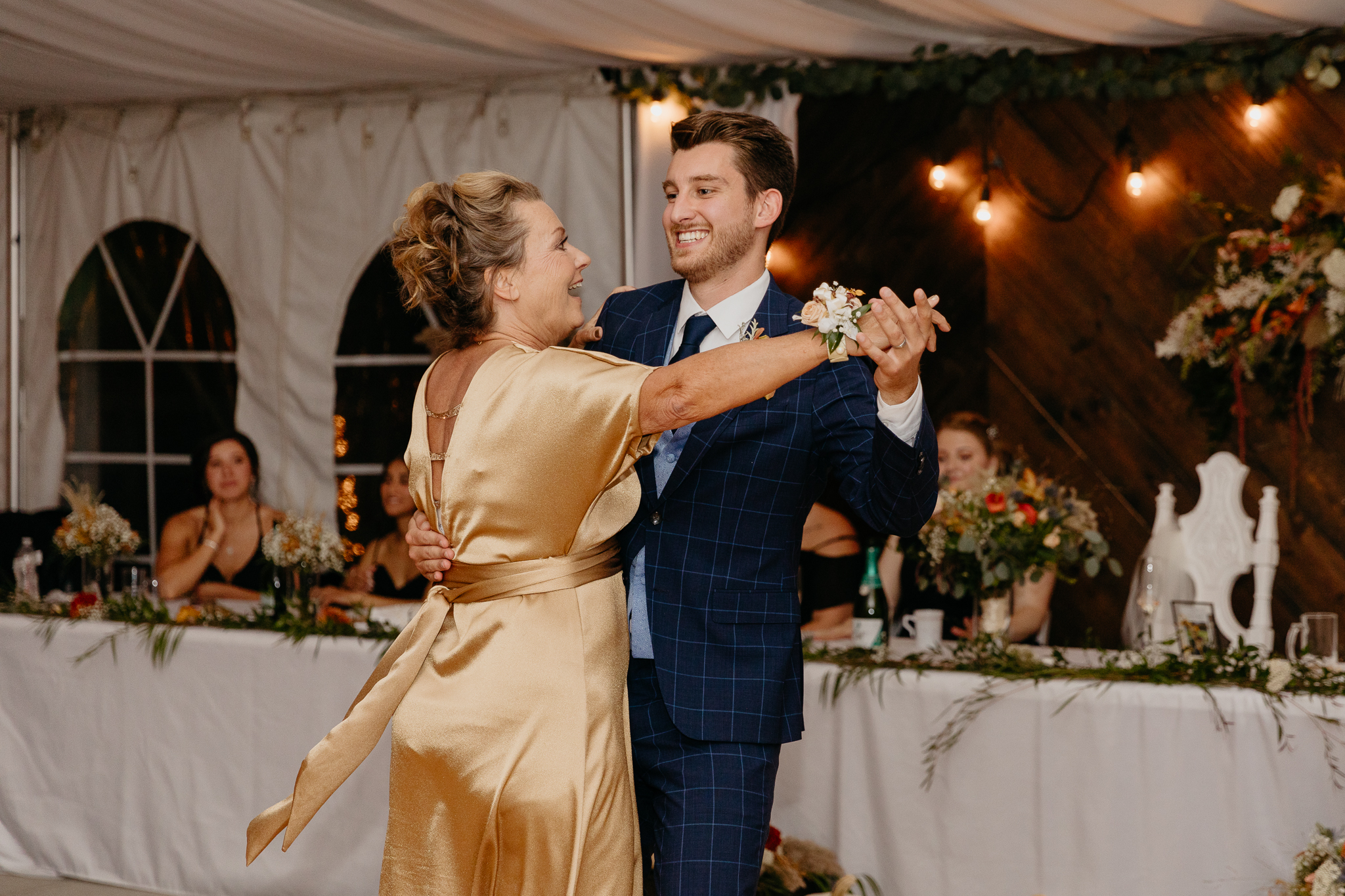 Groom dances with his mother on the dancefloor in a white tent wedding