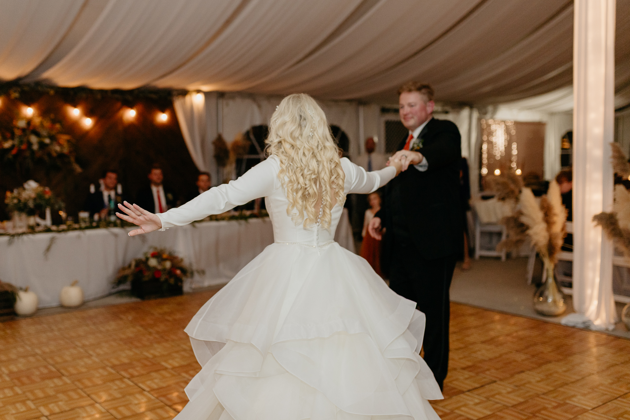 Bride dances with her father on the dancefloor in a white tent wedding