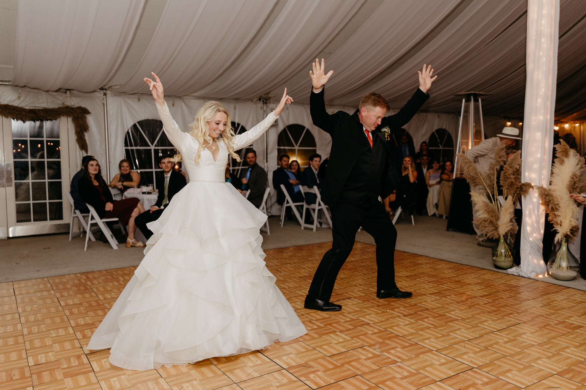 Bride and father dancing together during the father daughter dance, in a white tent wedding