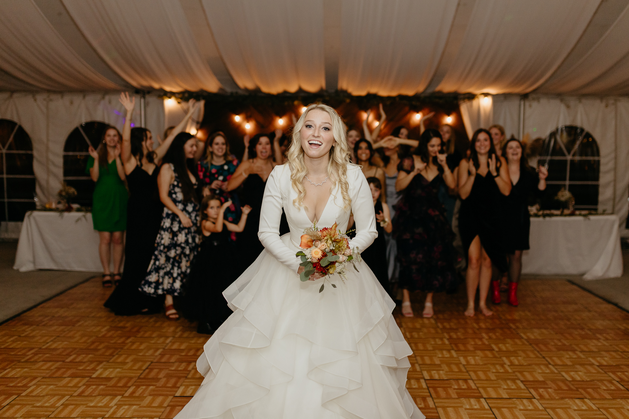 Bride tosses bouquet to all the single women on the dance floor