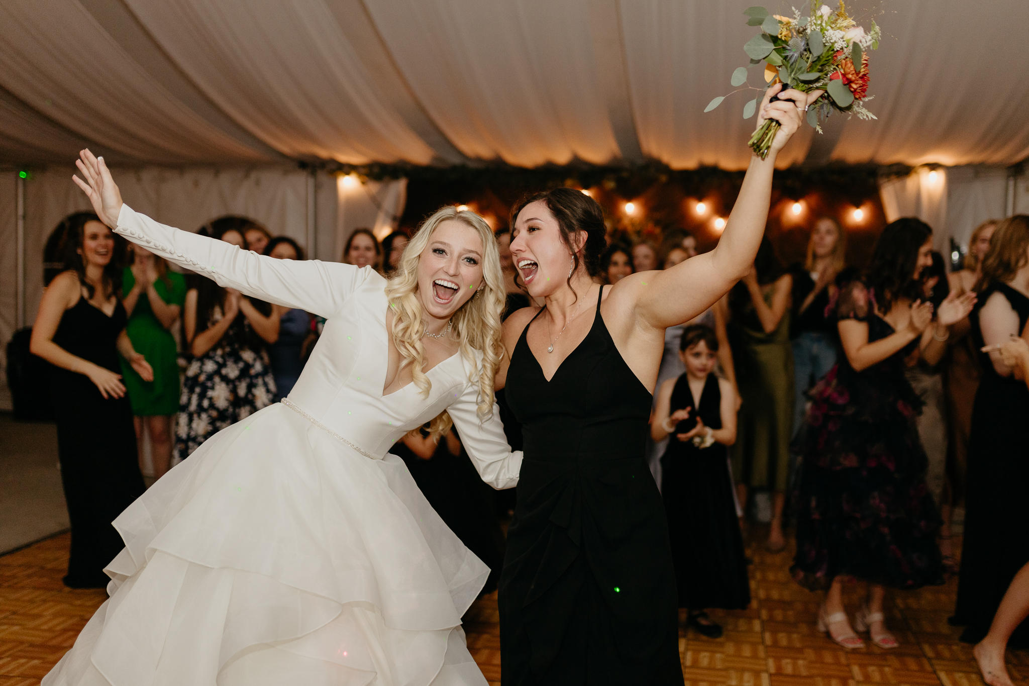 Bride tosses bouquet to all the single women on the dance floor