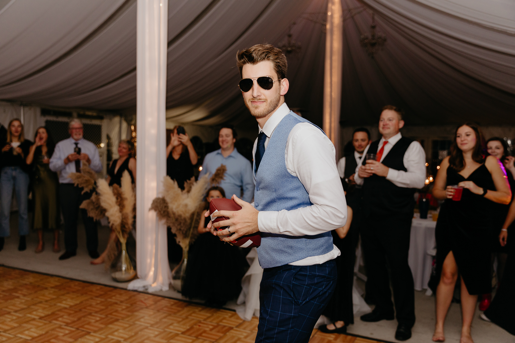 Groom tosses garter on football to all the single men on the dance floor