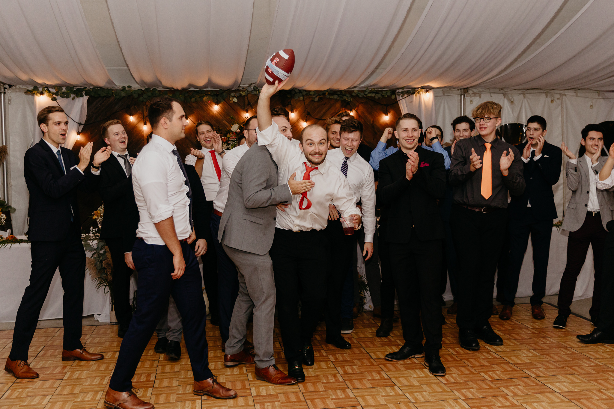 Groom tosses garter on football to all the single men on the dance floor