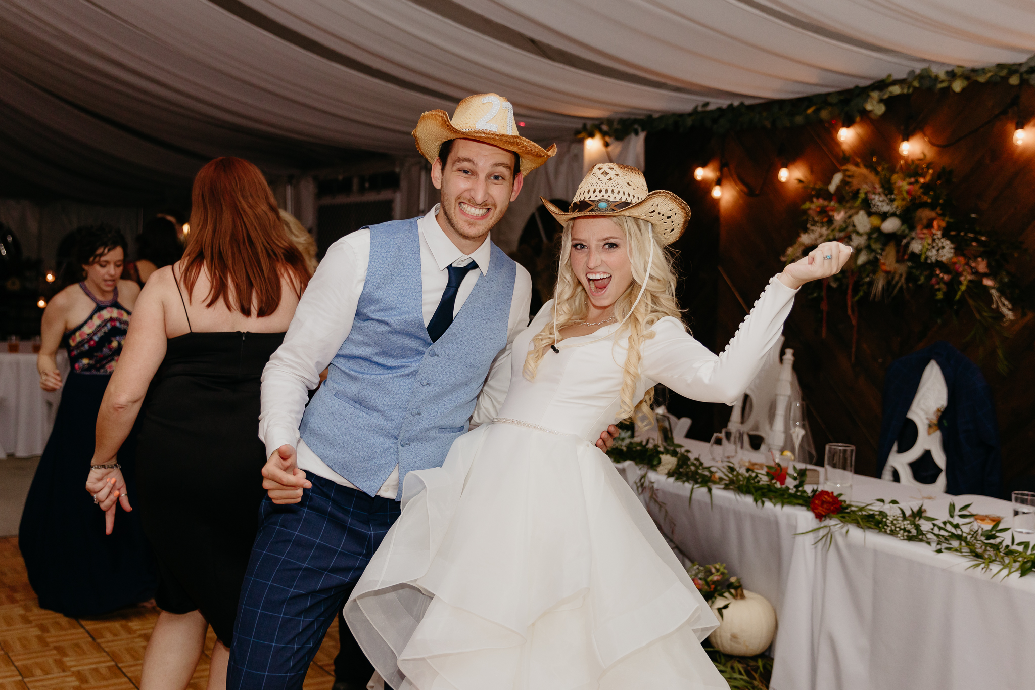Bride and groom smile and pose with cowboy hats on at their tent wedding reception in Chicago