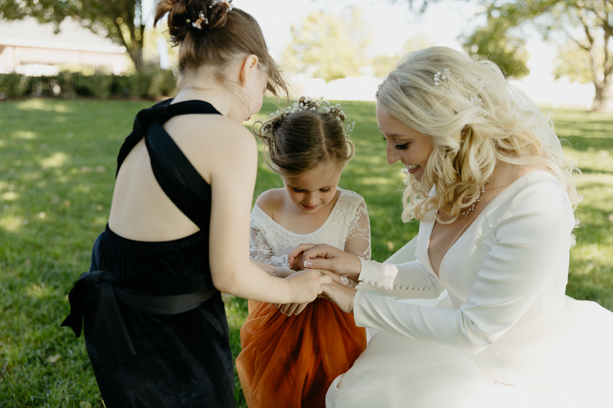 Bride helps flower girls put on bracelets during a fall wedding