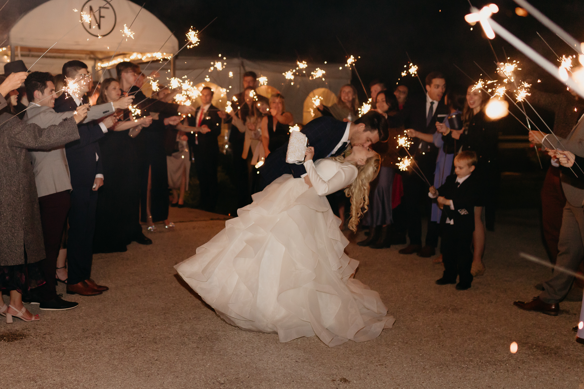 Bride and groom hold hands and run through sparklers and wedding guests at the end of their Northfork Farm Wedding