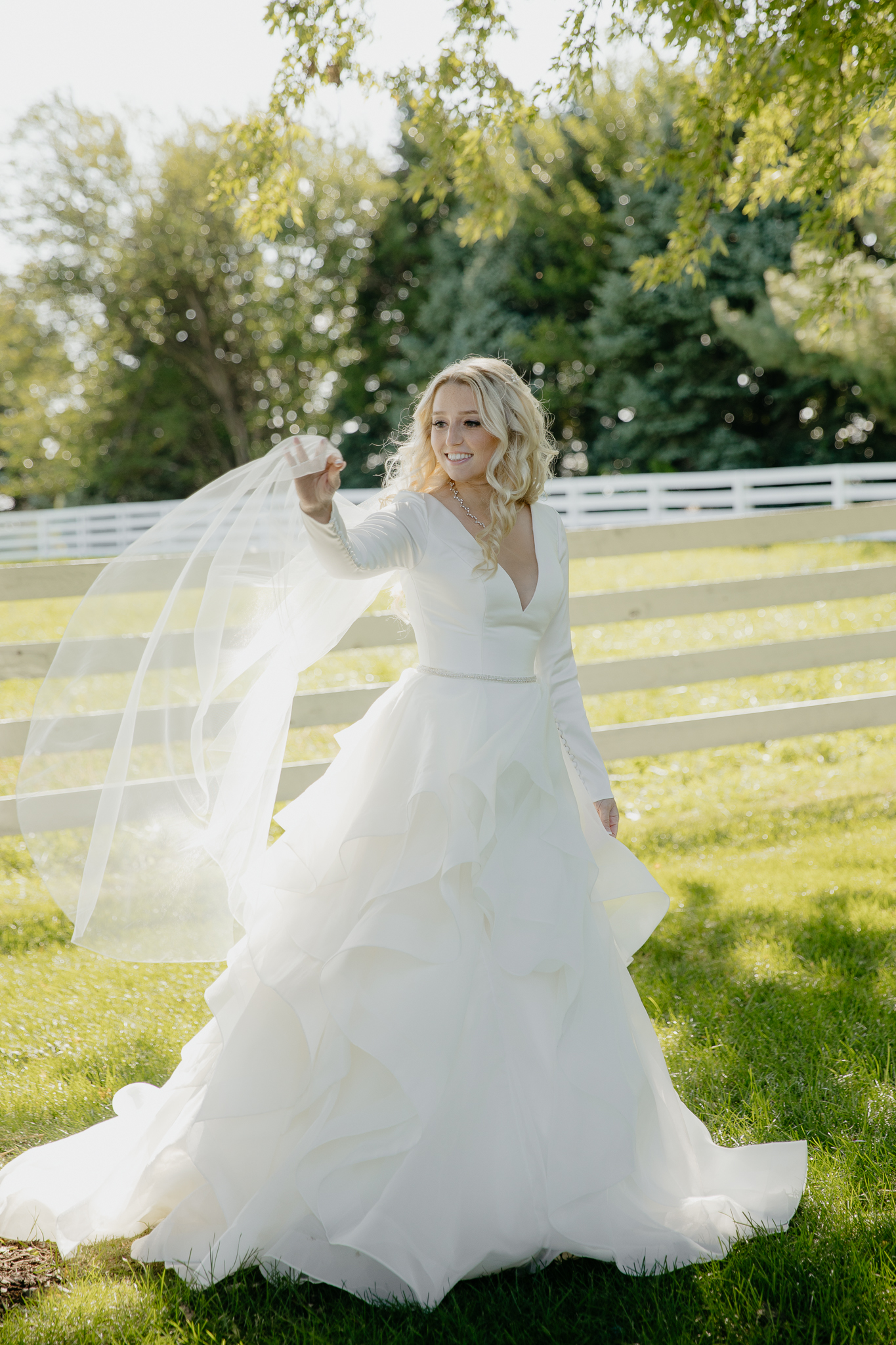 Portraits of bride in her wedding dress, with bouquet of flowers, near a horse pasture
