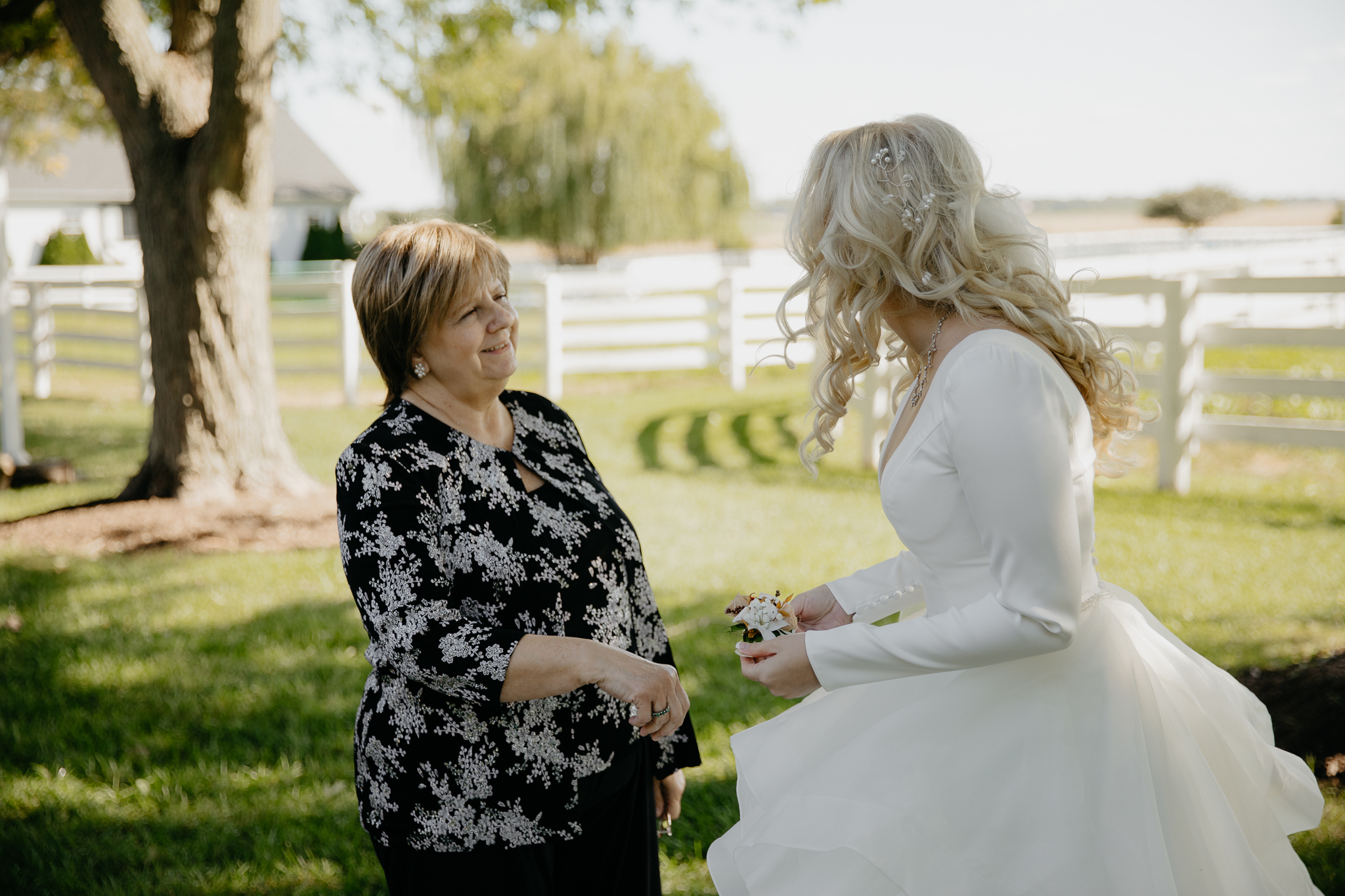 Bride helps aunt put on corsage for a fall wedding