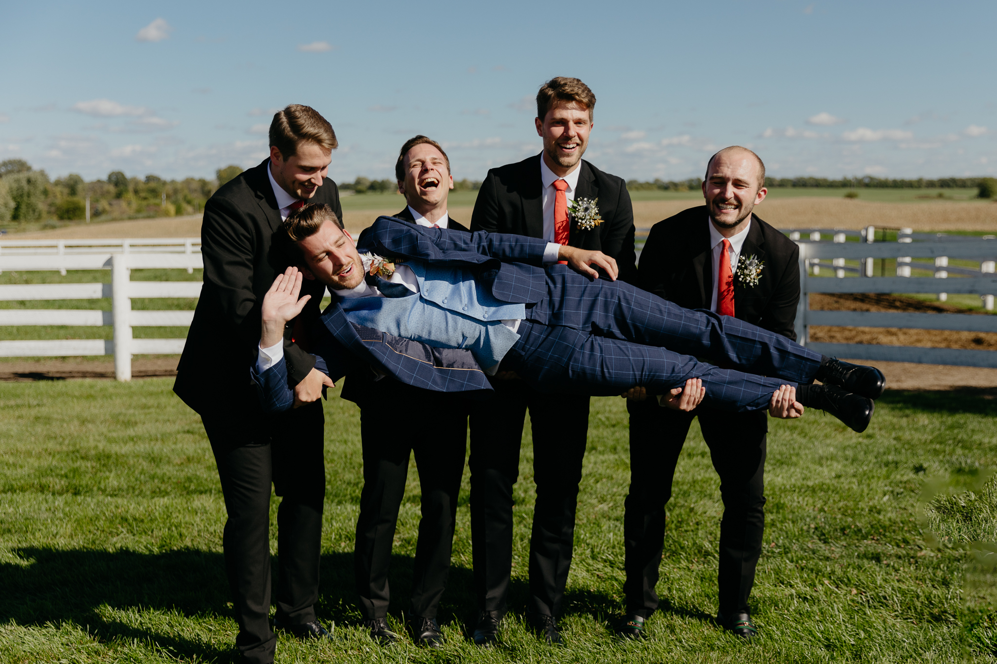 Groomsmen hold groom sideways for group photos