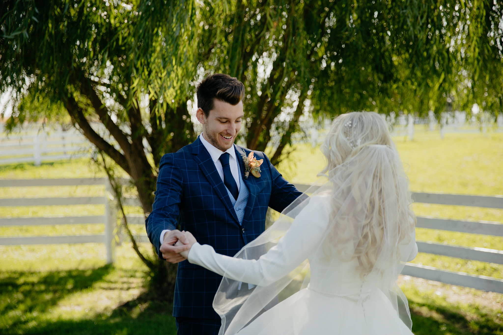 Groom admires his bride by a willow tree