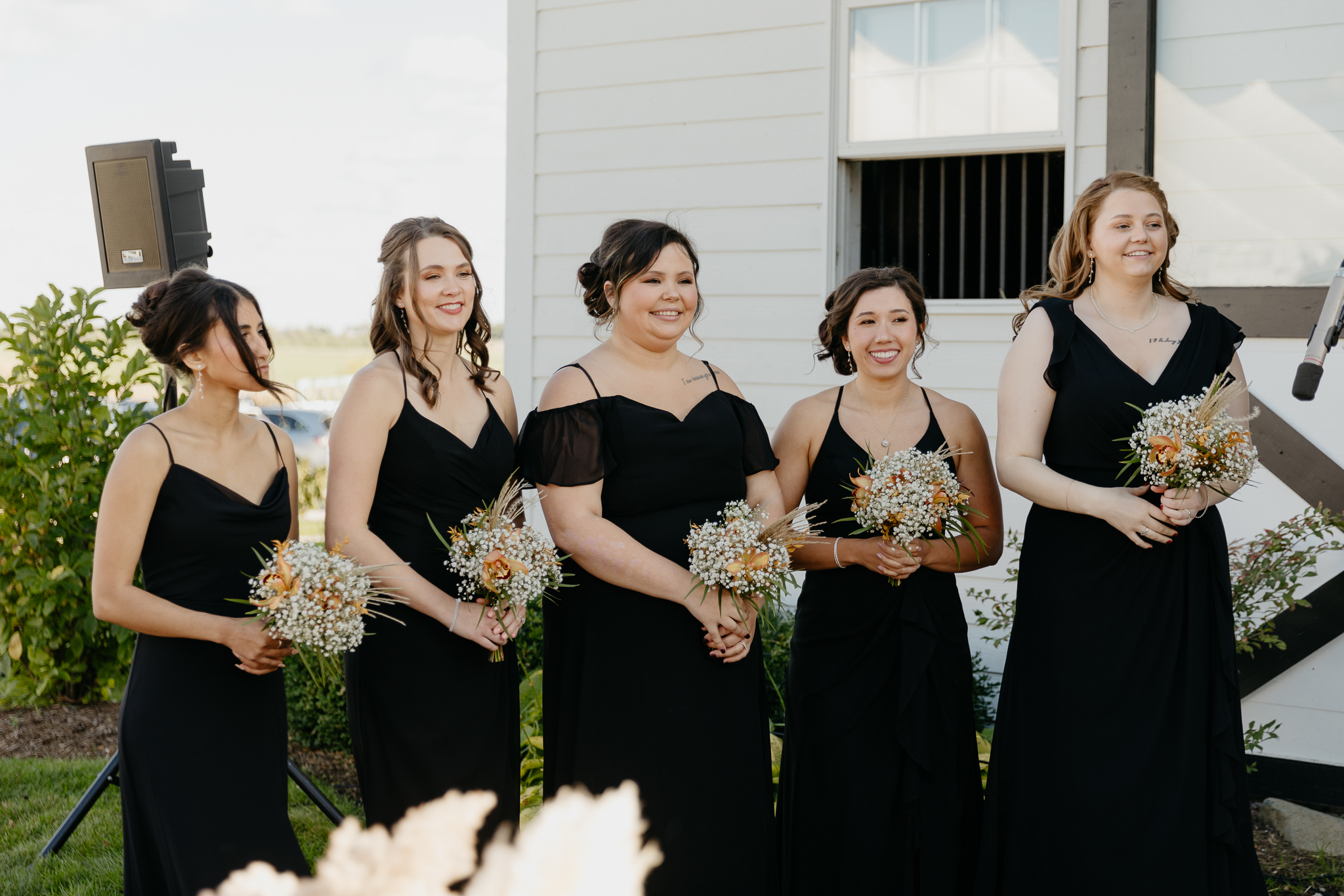 Bridesmaids lined up and watching the wedding ceremony at a horse farm