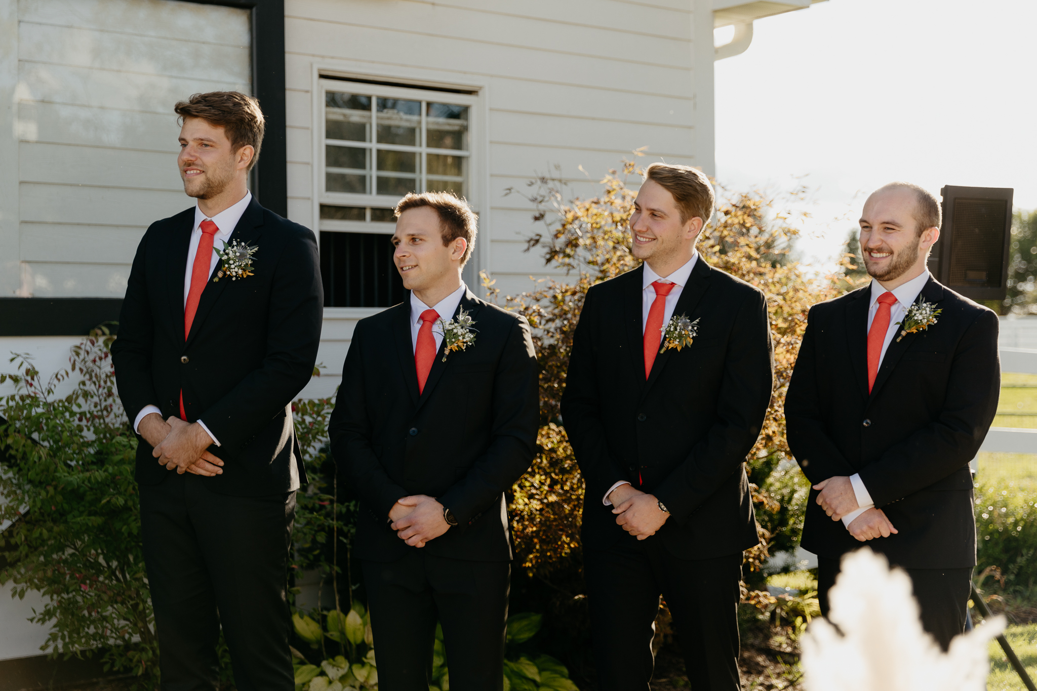 Groomsmen lined up and watching the wedding ceremony at a horse farm
