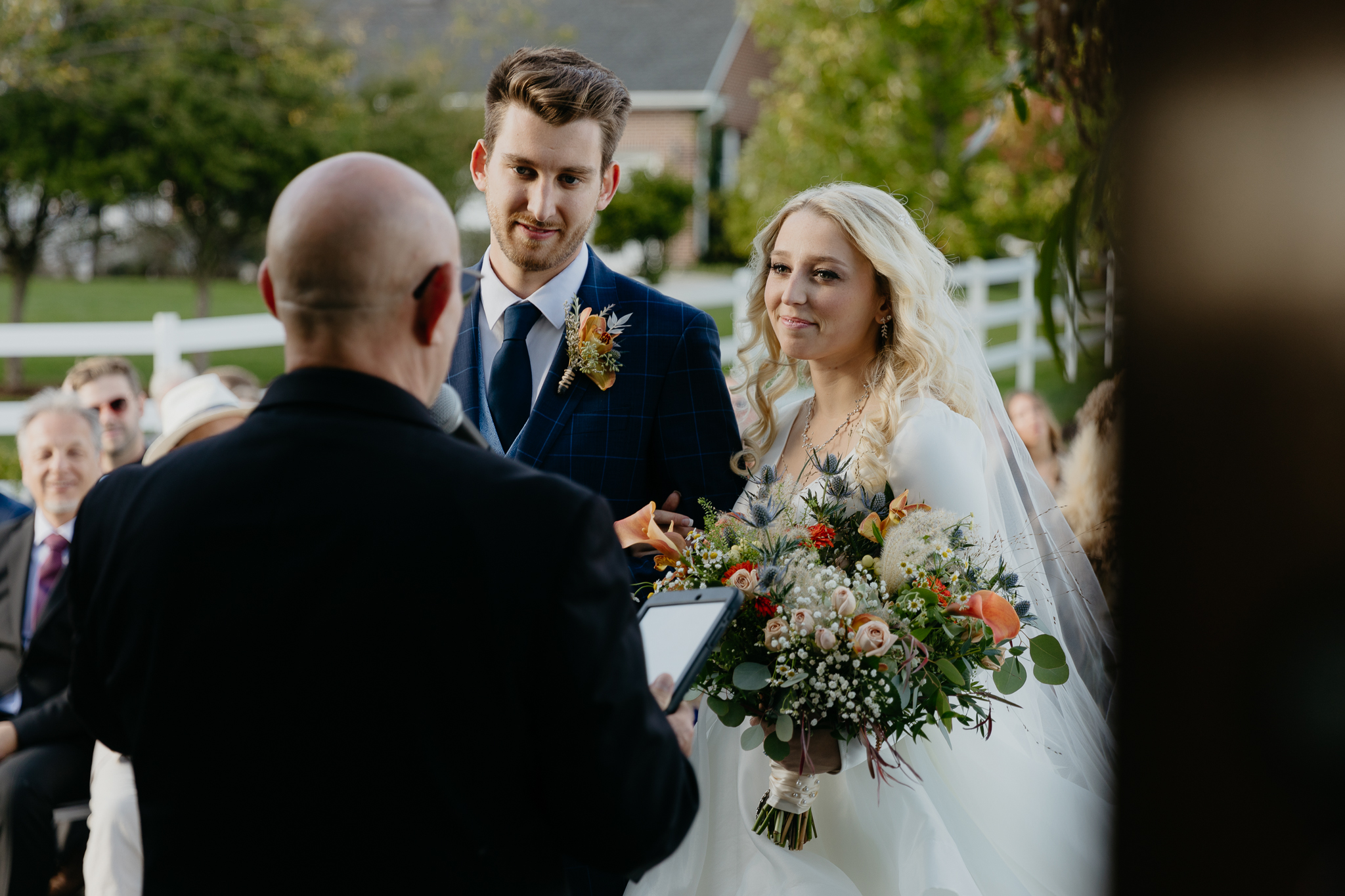 Bride and groom smiling and listening at the altar of their outdoor fall wedding ceremony at Northfork Farm
