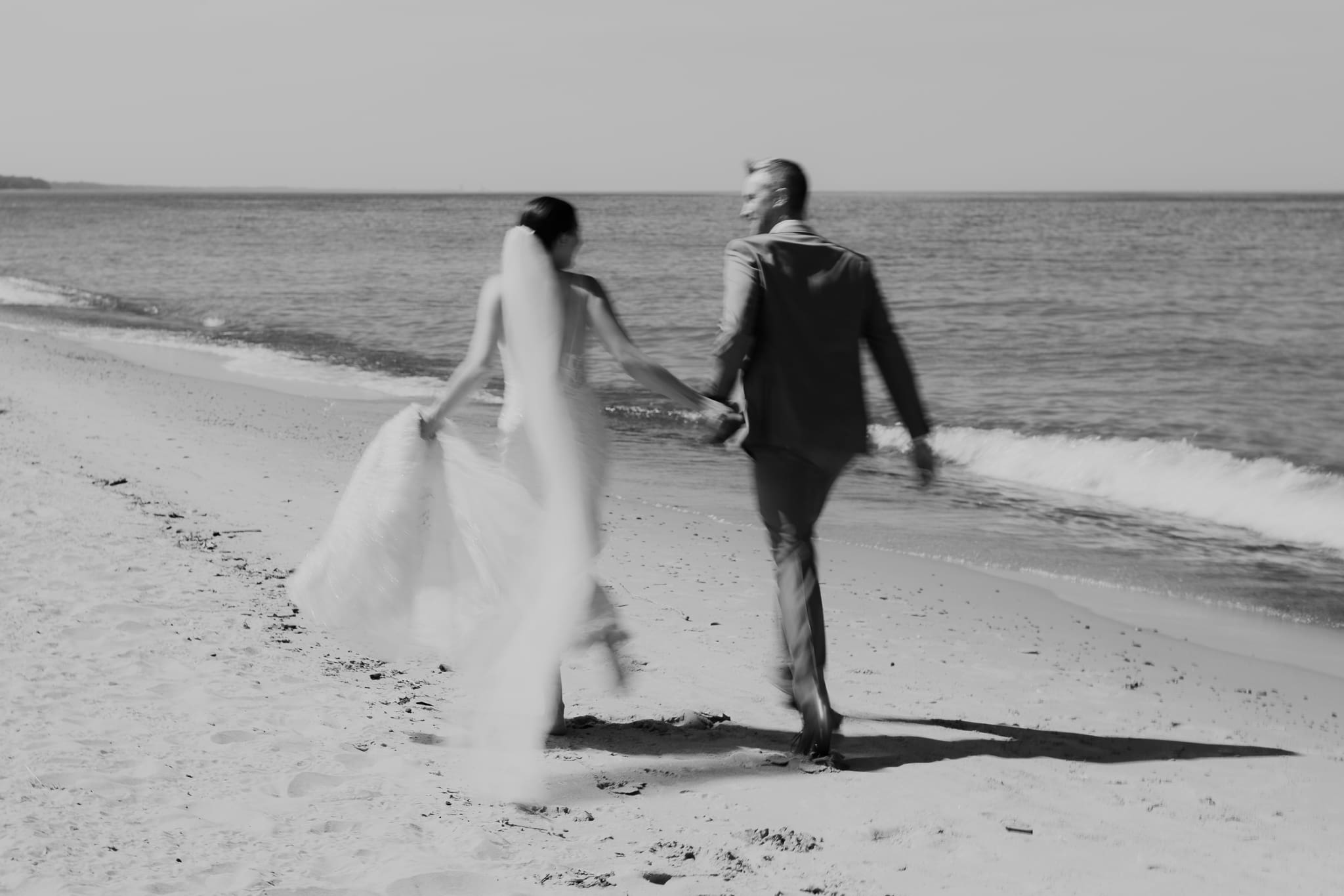 Bride and groom embracing and enjoying their Warren Dunes State Park elopement while running along the beach