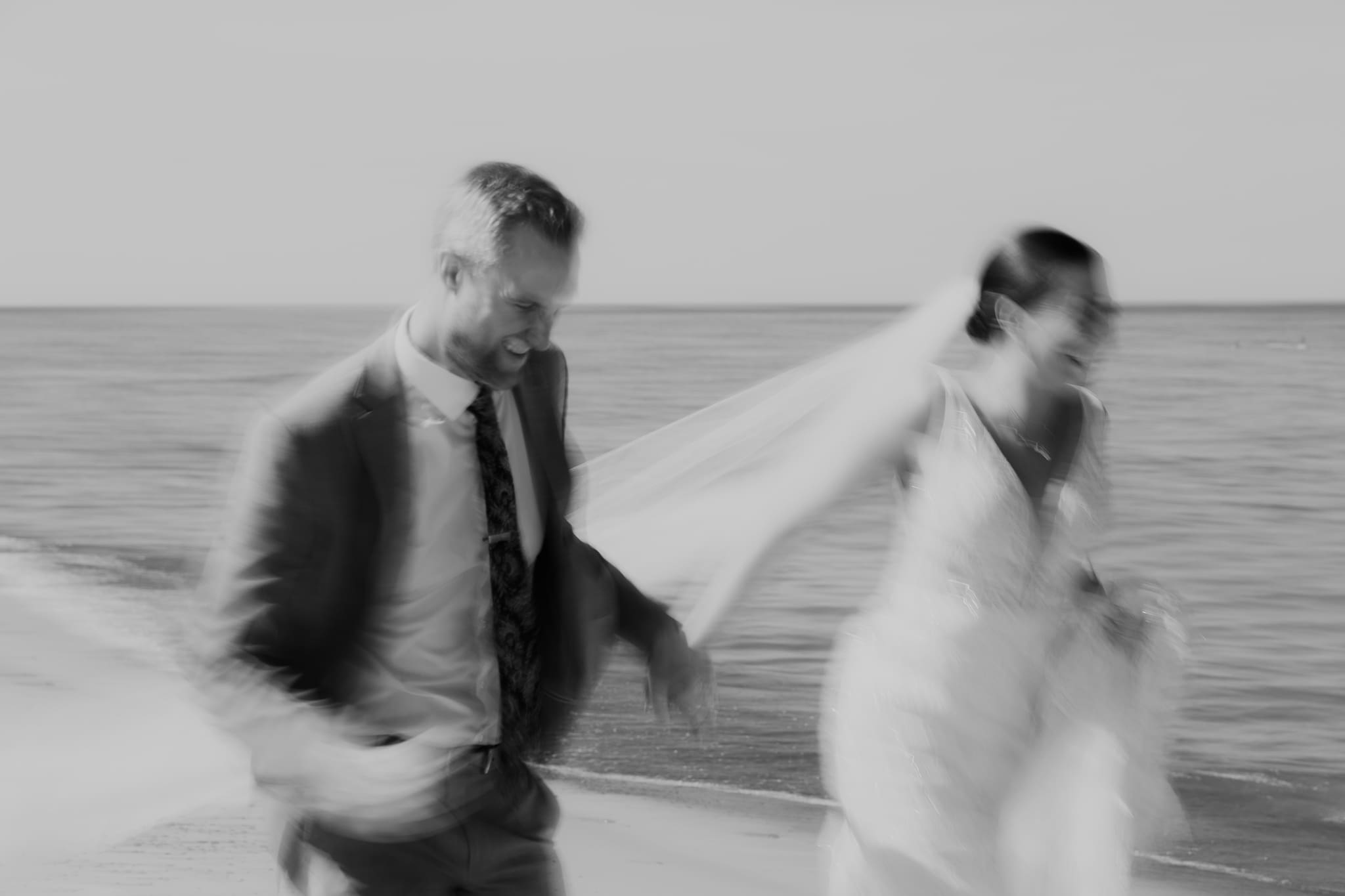 Bride and groom embracing and enjoying their Warren Dunes State Park elopement while running along the beach