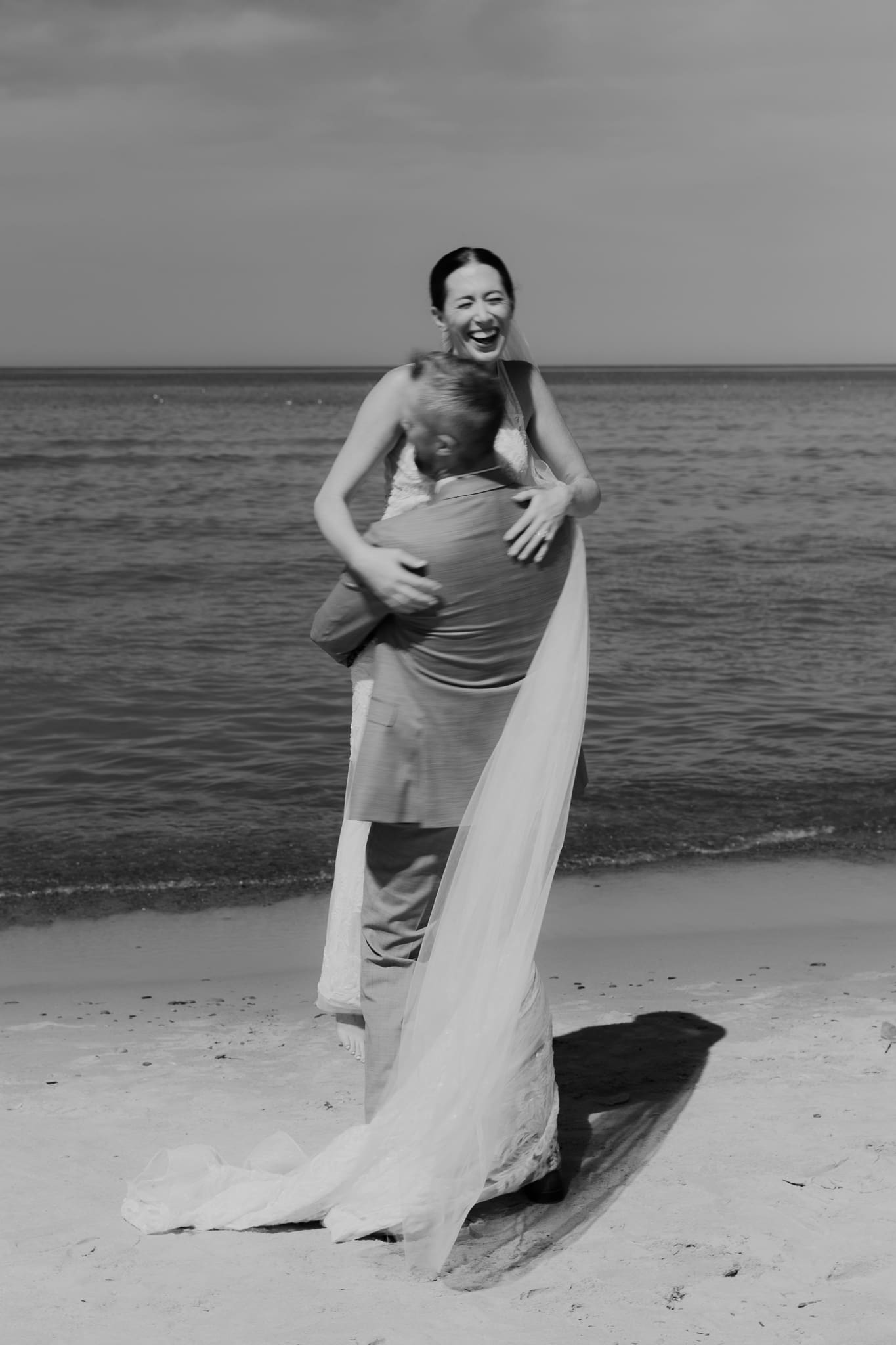 Groom lifts bride in the air and spins her around during their Lake Michigan beach elopement