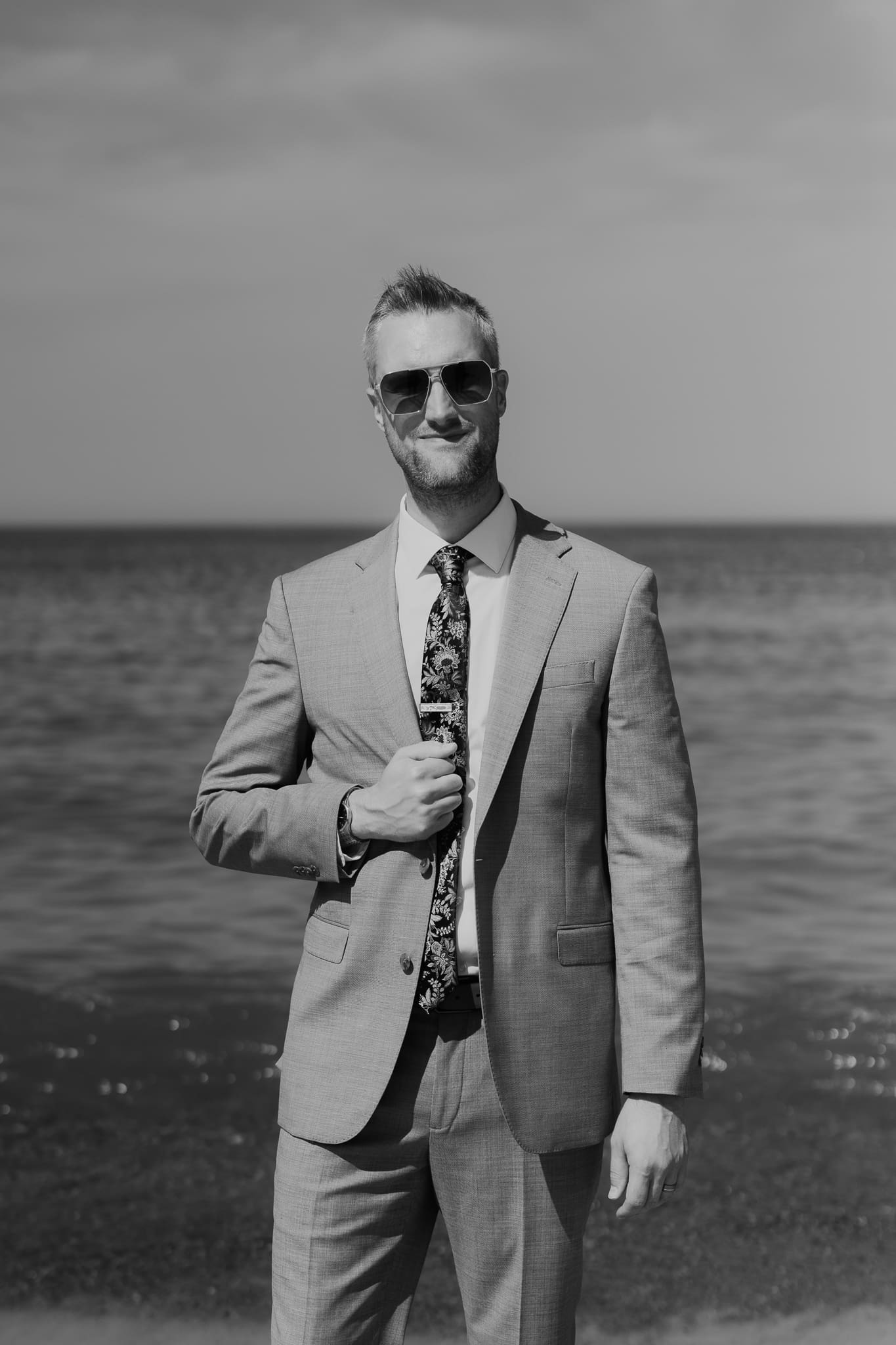 Groom poses along the shoreline of Lake Michigan