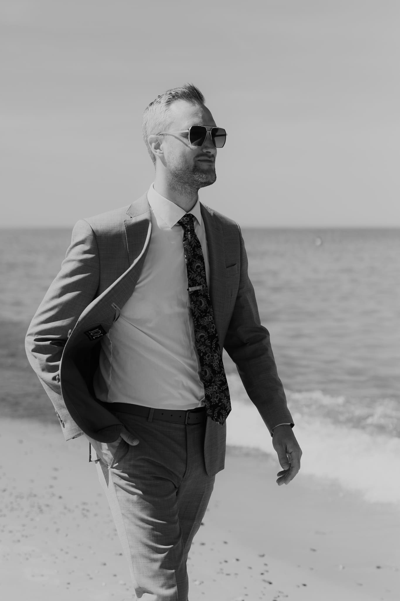 Groom poses along the shoreline of Lake Michigan
