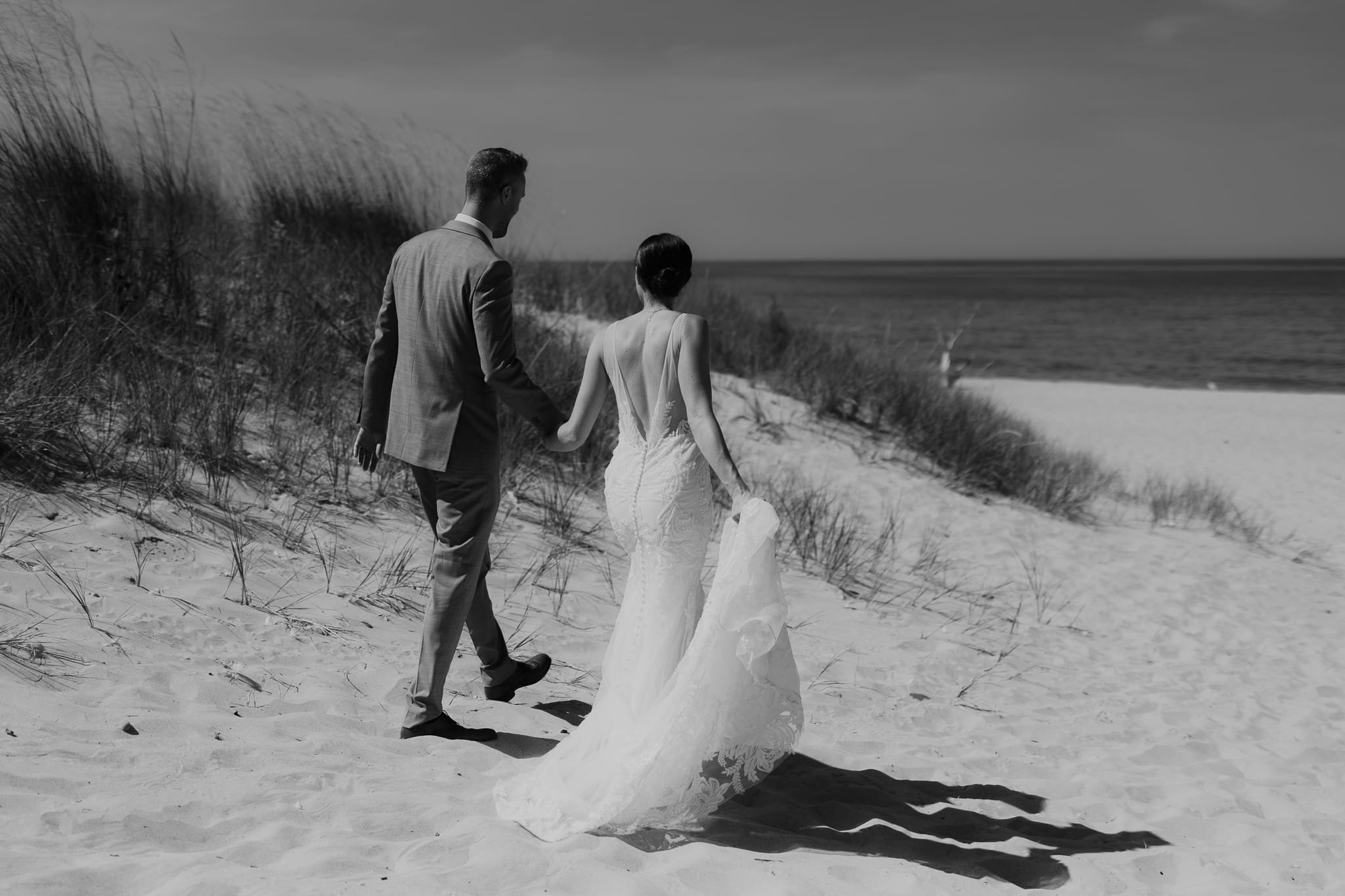 Bride and groom embrace and kiss next to sand dunes during their Lake Michigan elopement